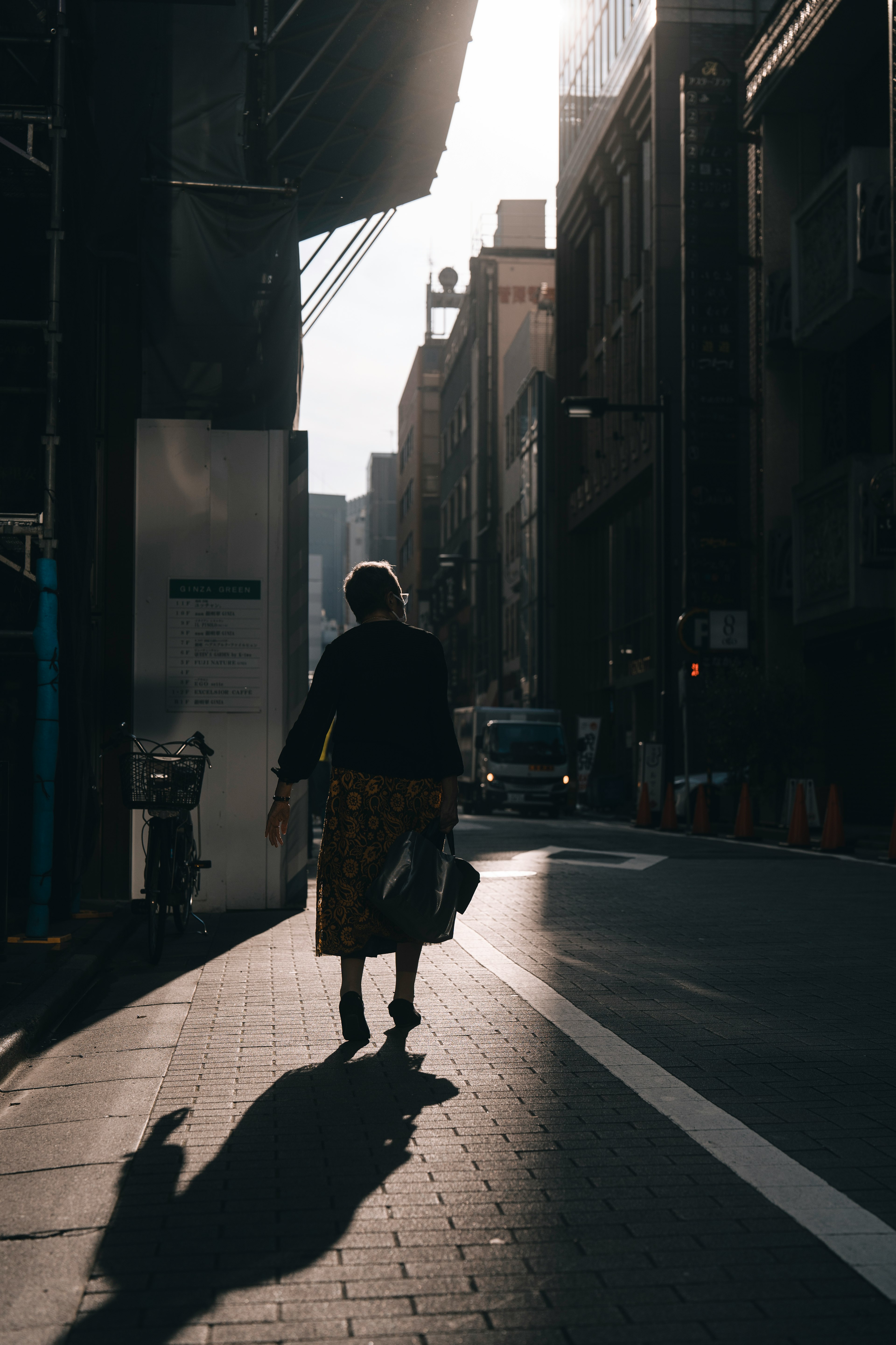 Silhouette of a woman walking in the street with urban buildings