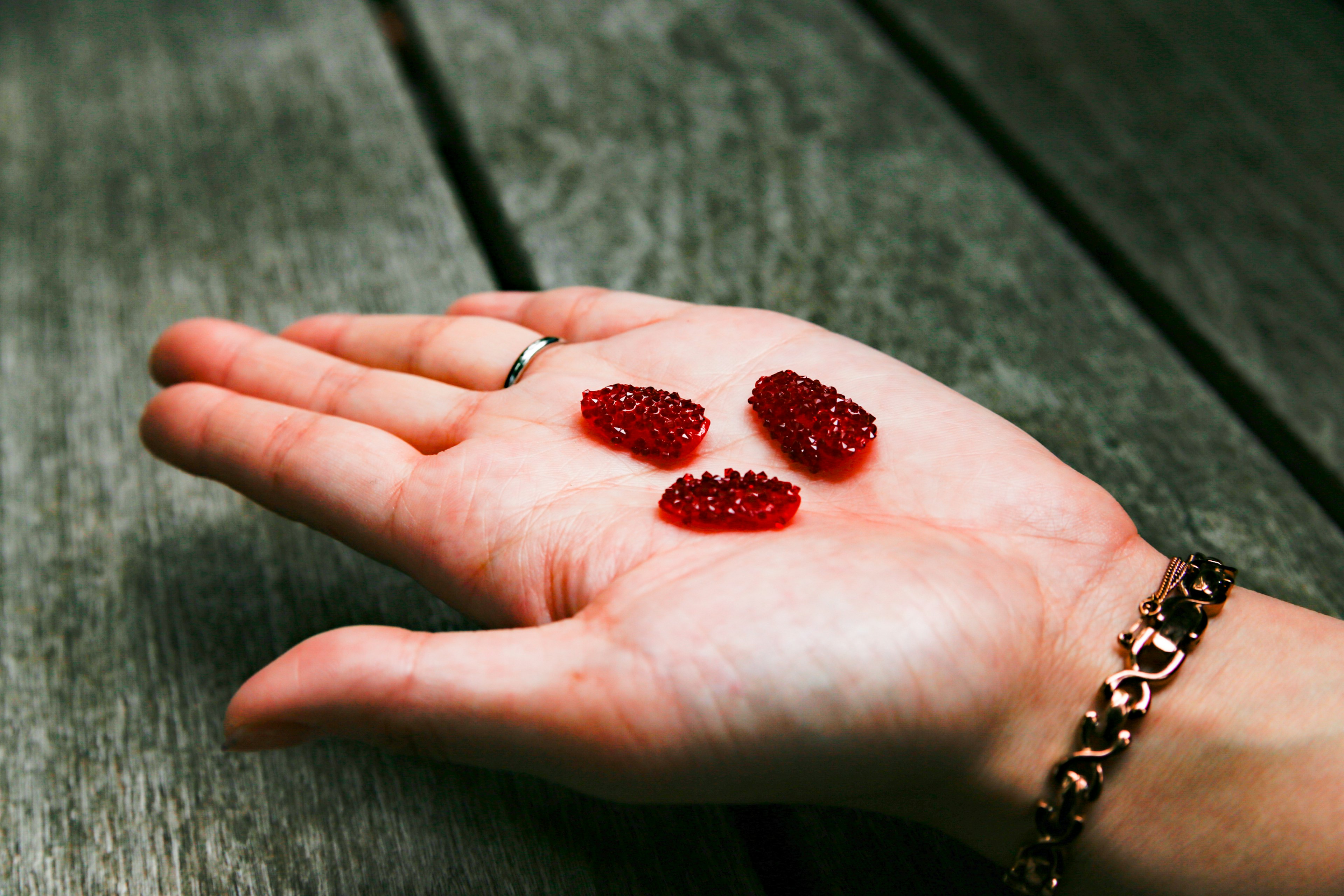 Drei rote Gummibärchen auf einer offenen Handfläche