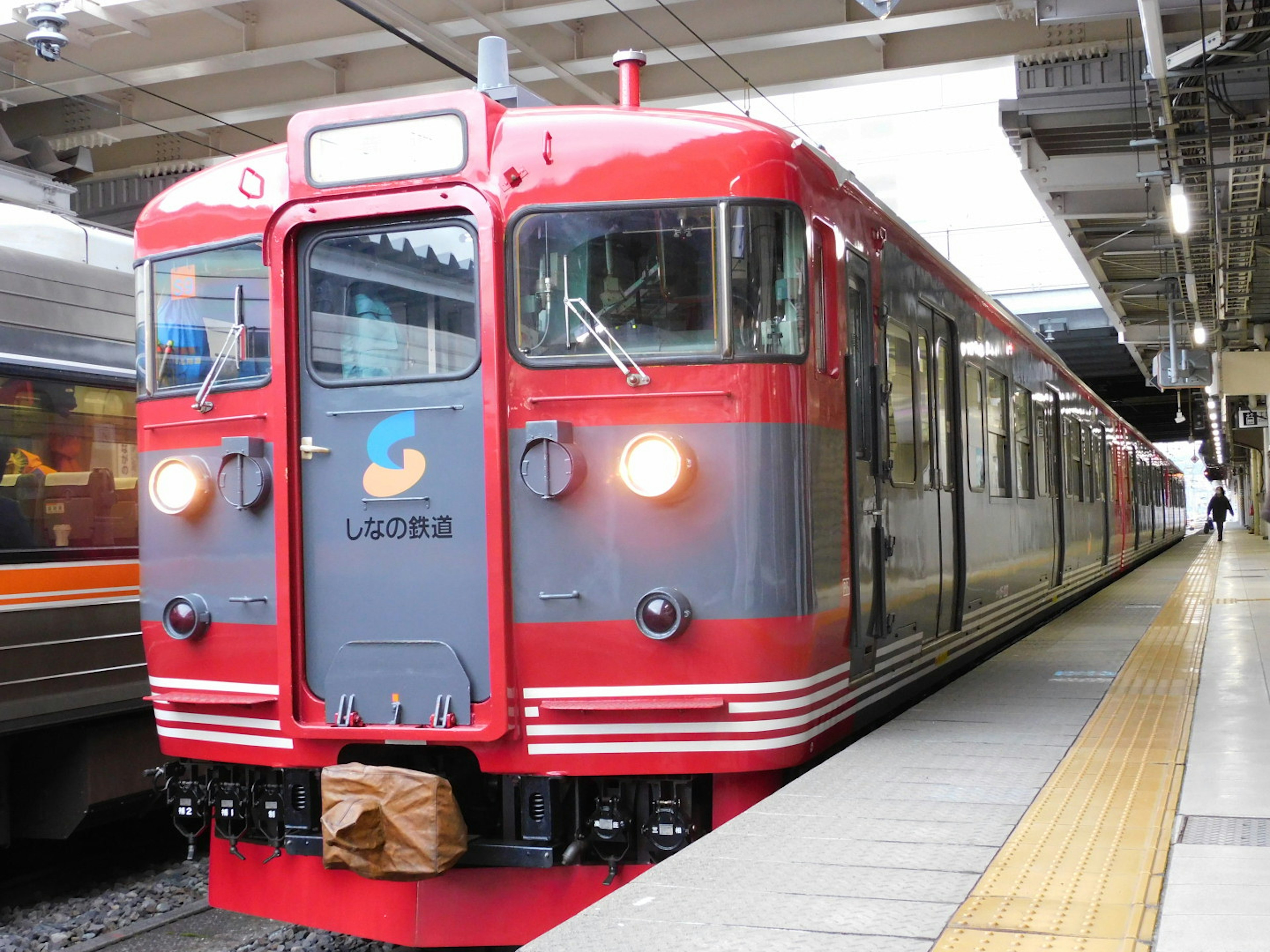 赤い列車が駅のプラットフォームに停車している