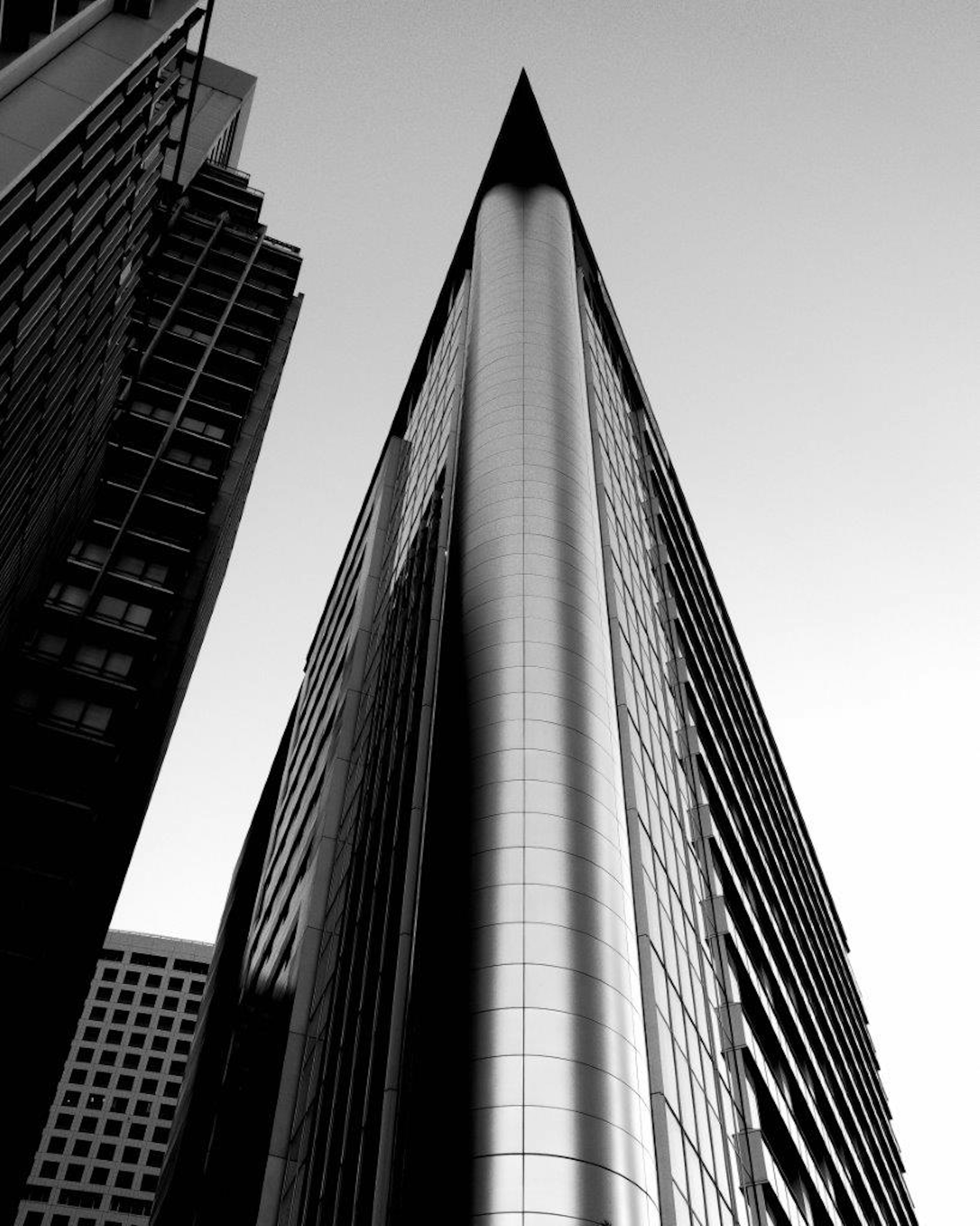 A tall skyscraper with a sharp pointed shape captured in black and white