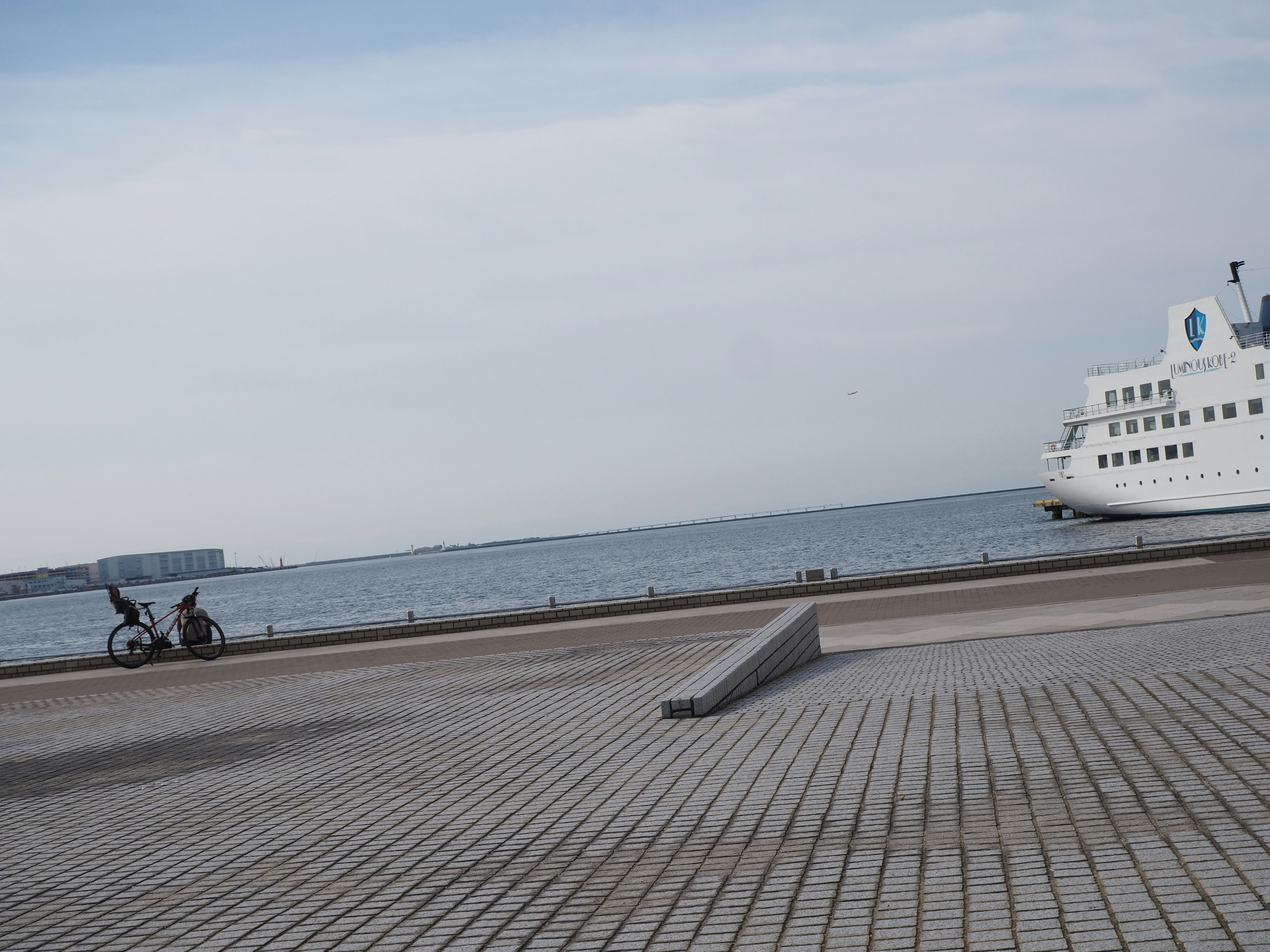 Scenic waterfront with a docked ship and paved walkway