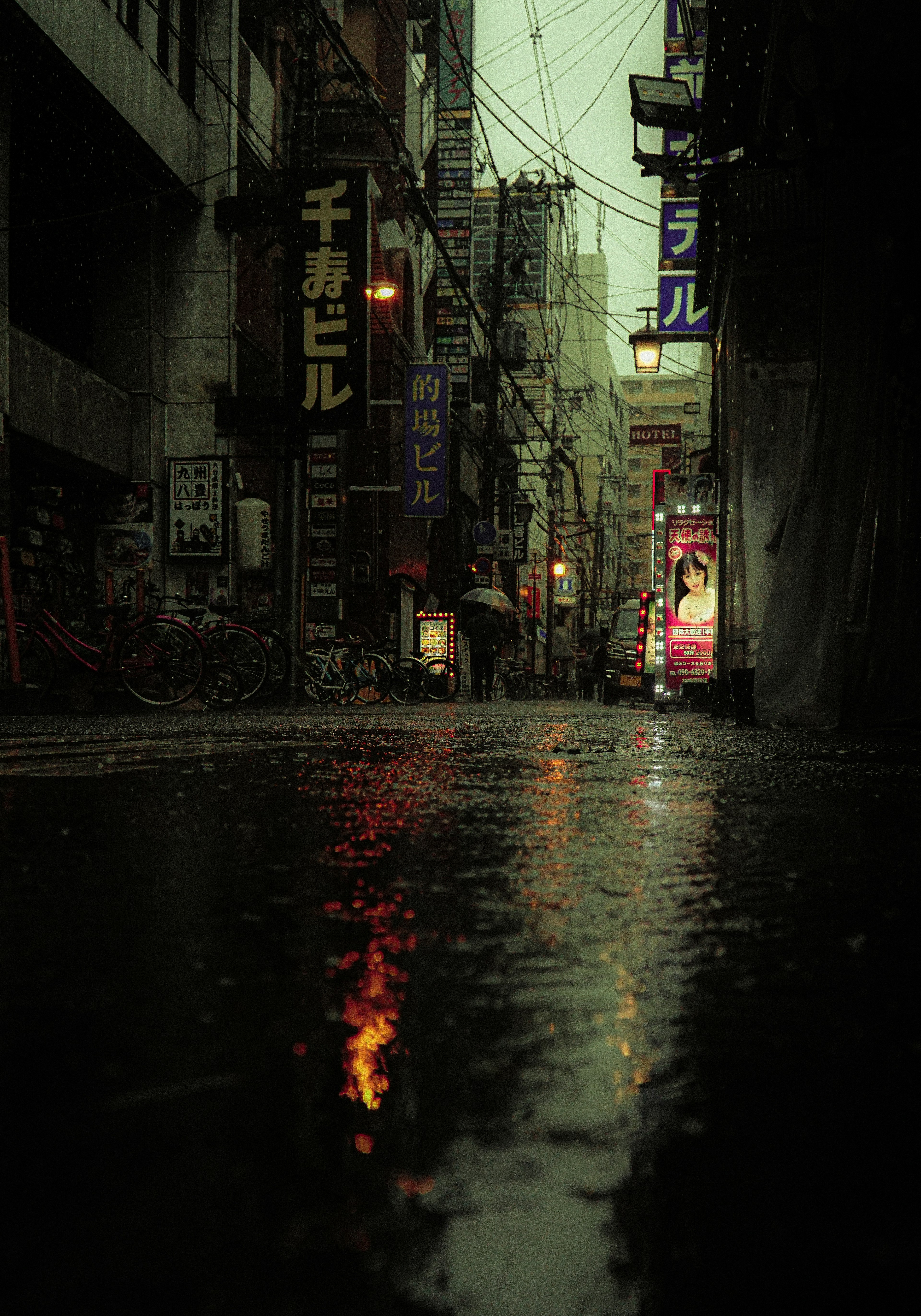 Rain-soaked street scene neon signs reflecting on wet pavement moody atmosphere