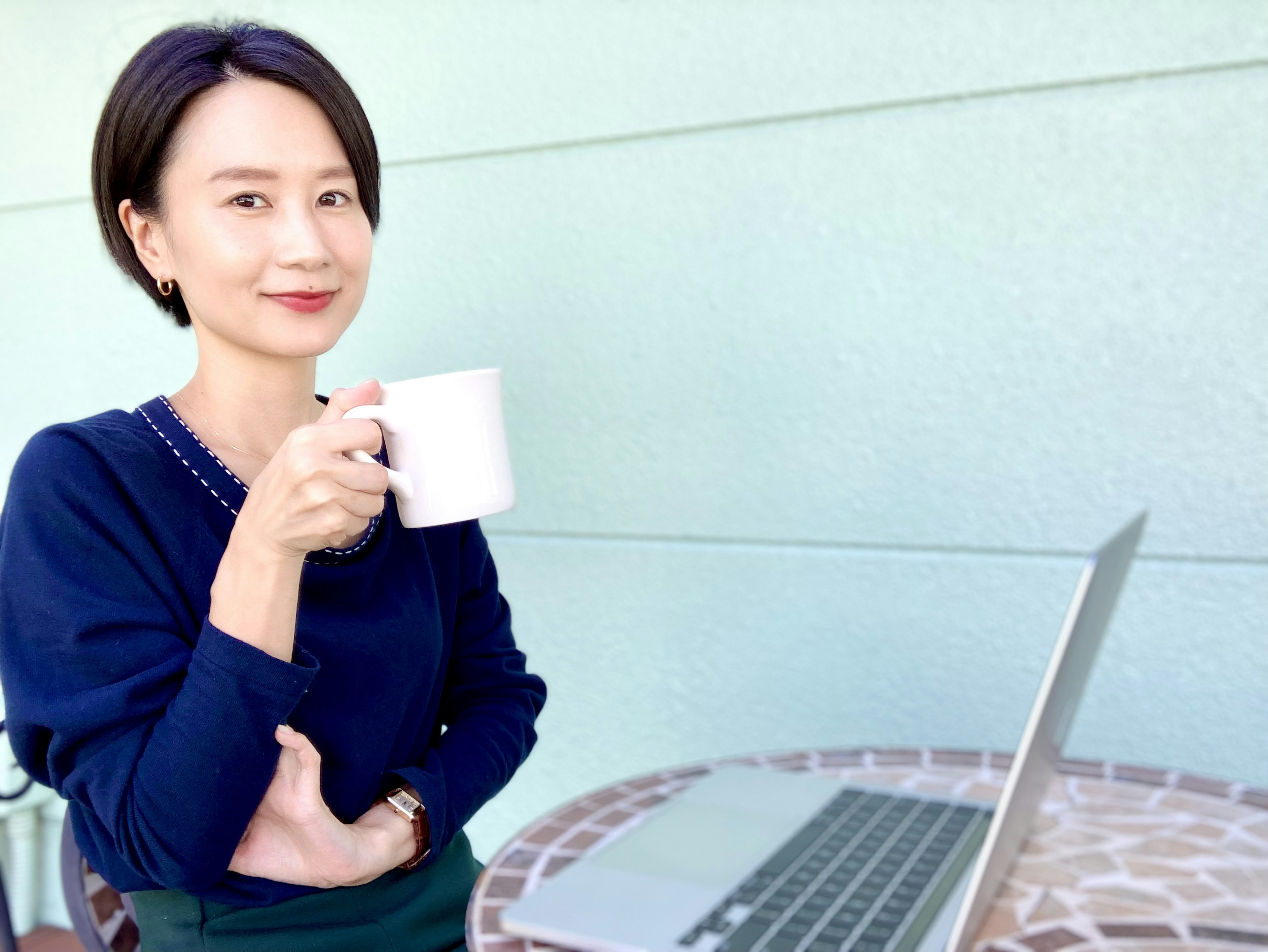 Donna che tiene una tazza di caffè seduta davanti a un laptop