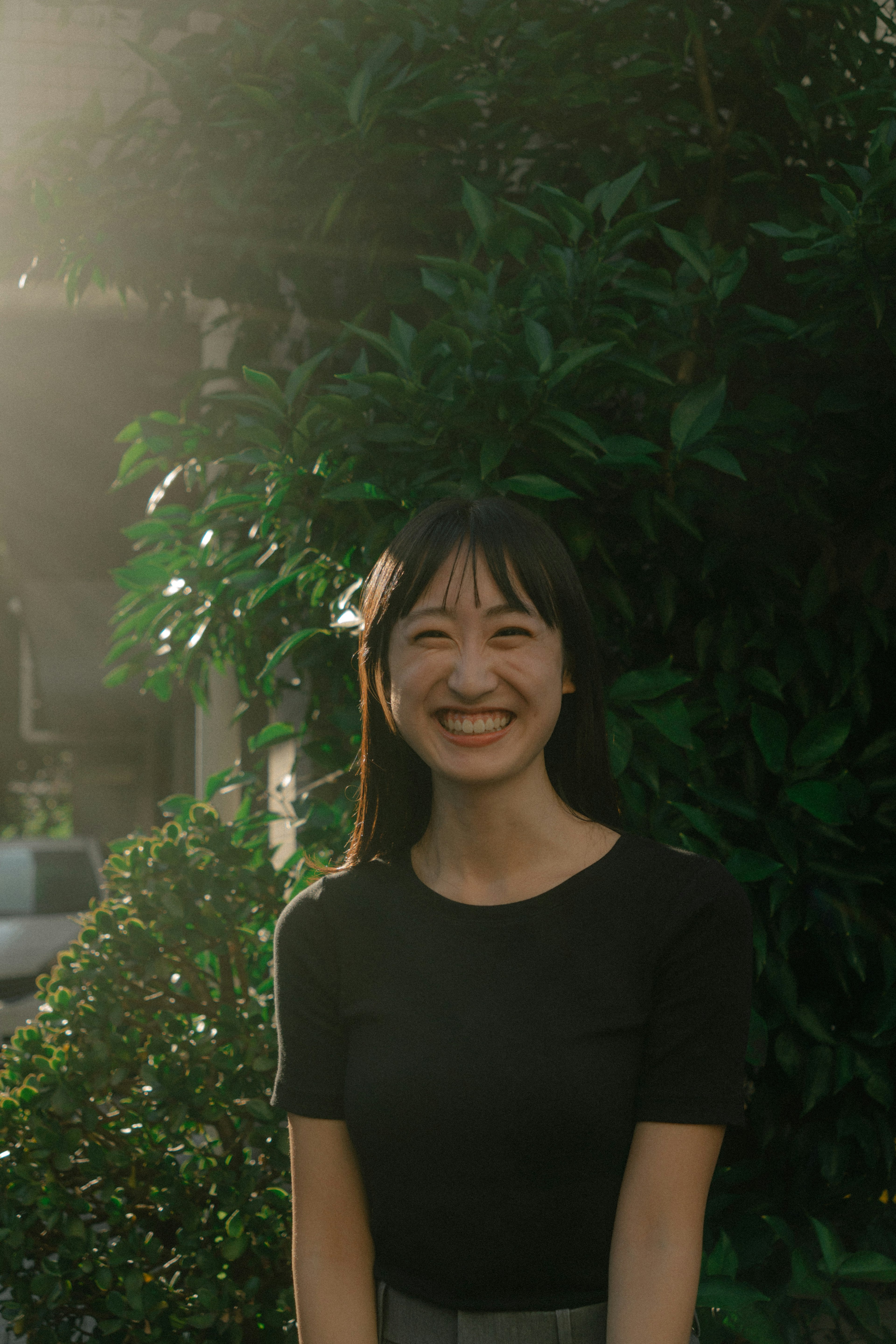 Portrait d'une femme souriante devant un feuillage vert