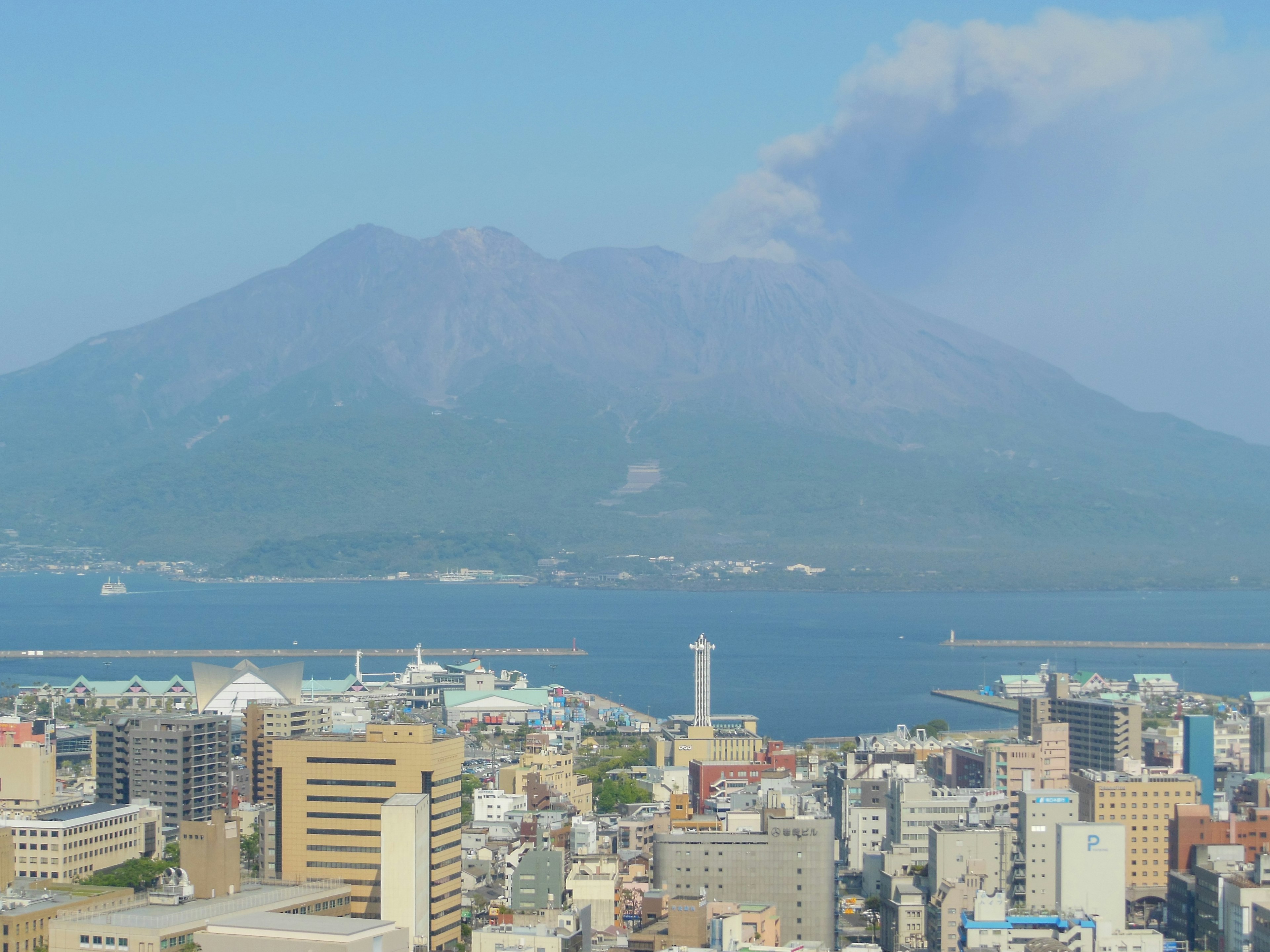 桜島の背景に広がる鹿児島市の風景と青い海