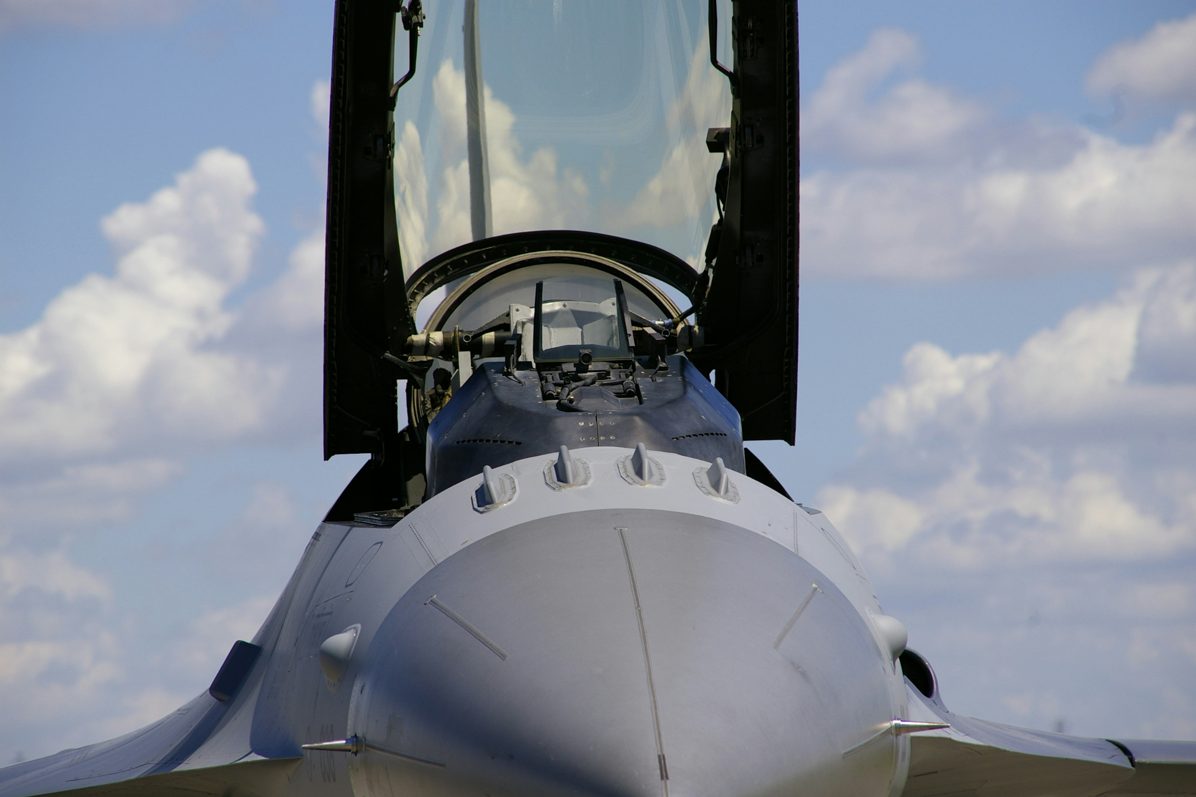 Image of a fighter jet cockpit with a cloudy sky background