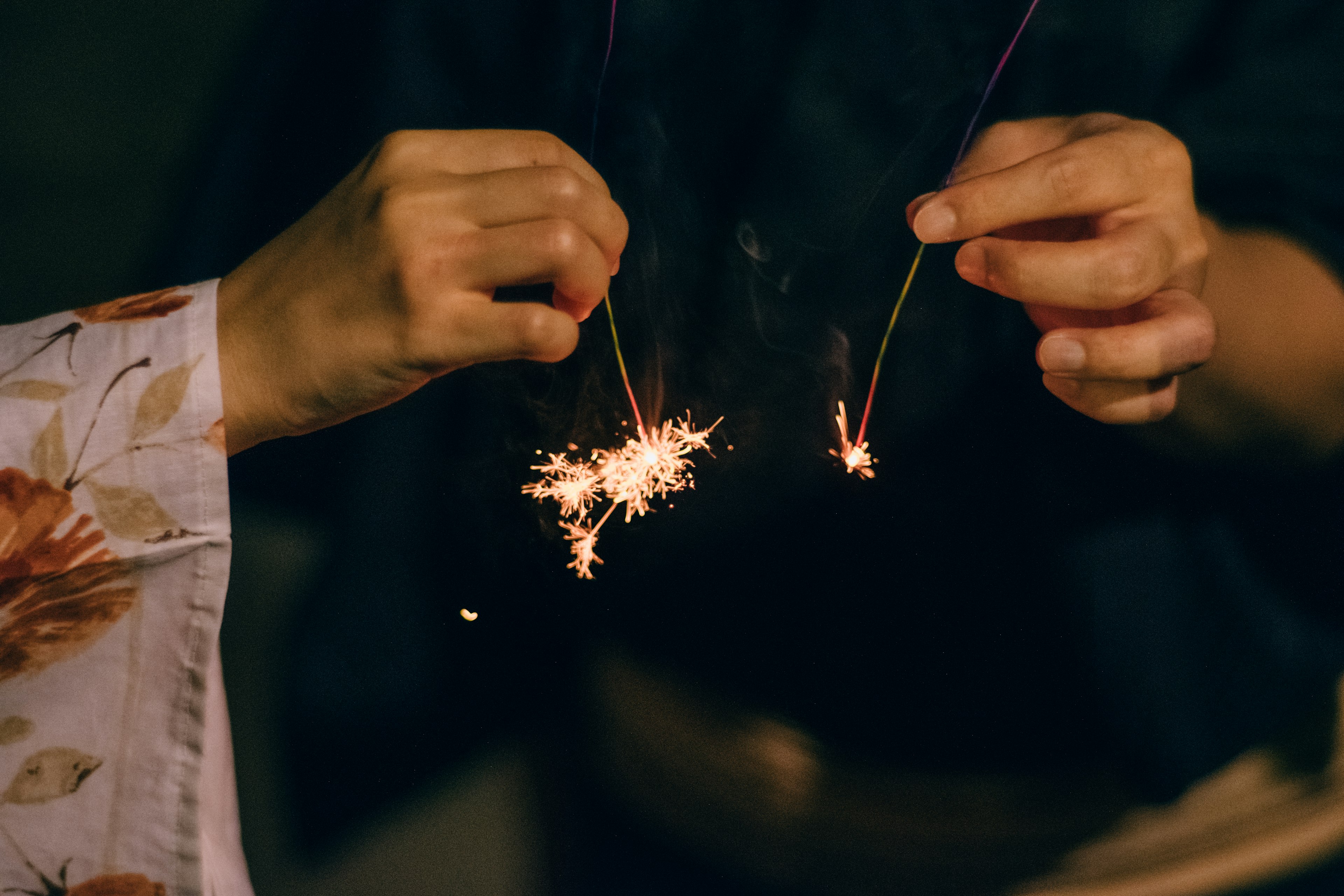 Two hands holding sparklers with bright sparks