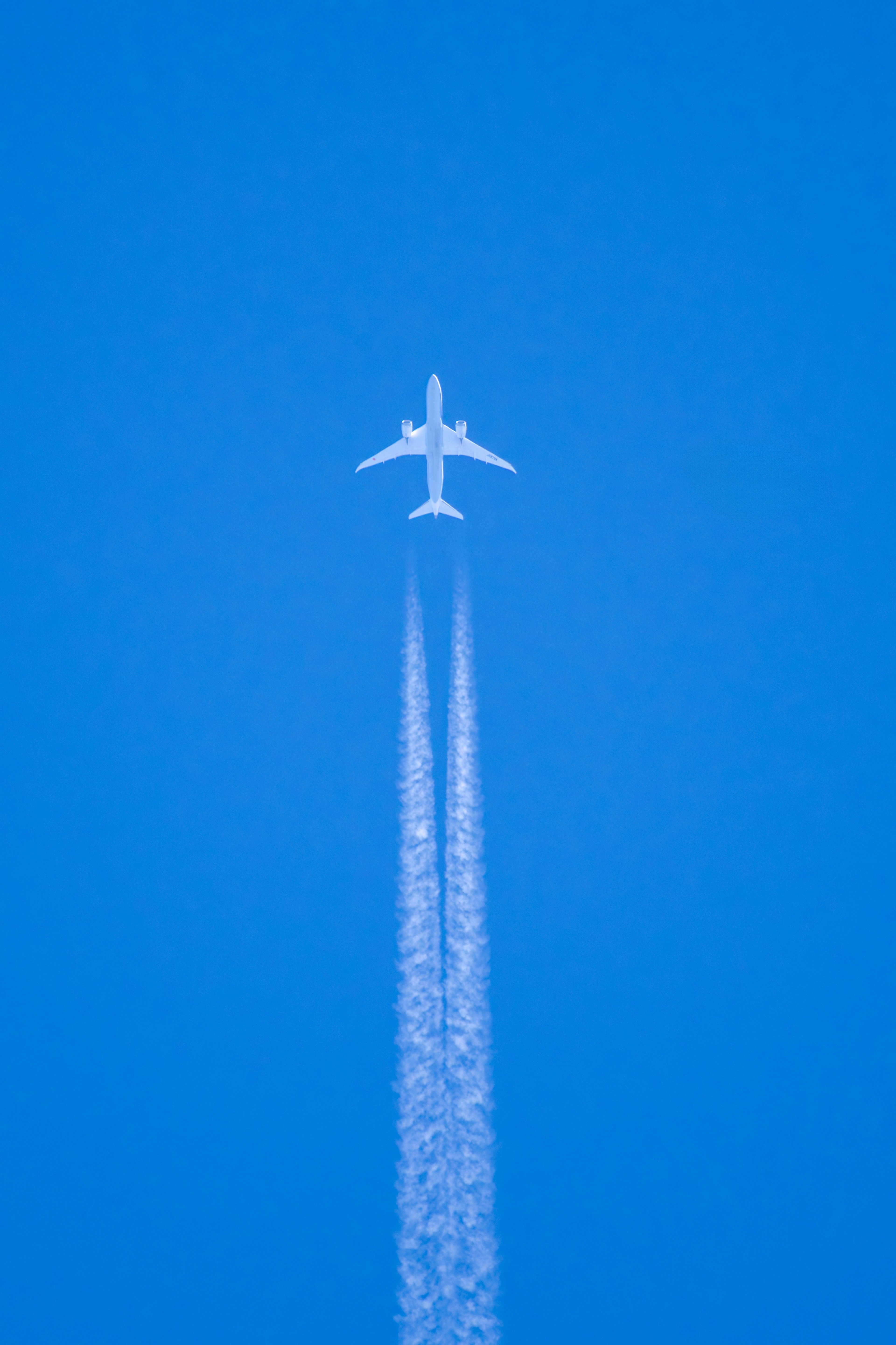 Aereo che vola in un cielo blu chiaro lasciando scie bianche