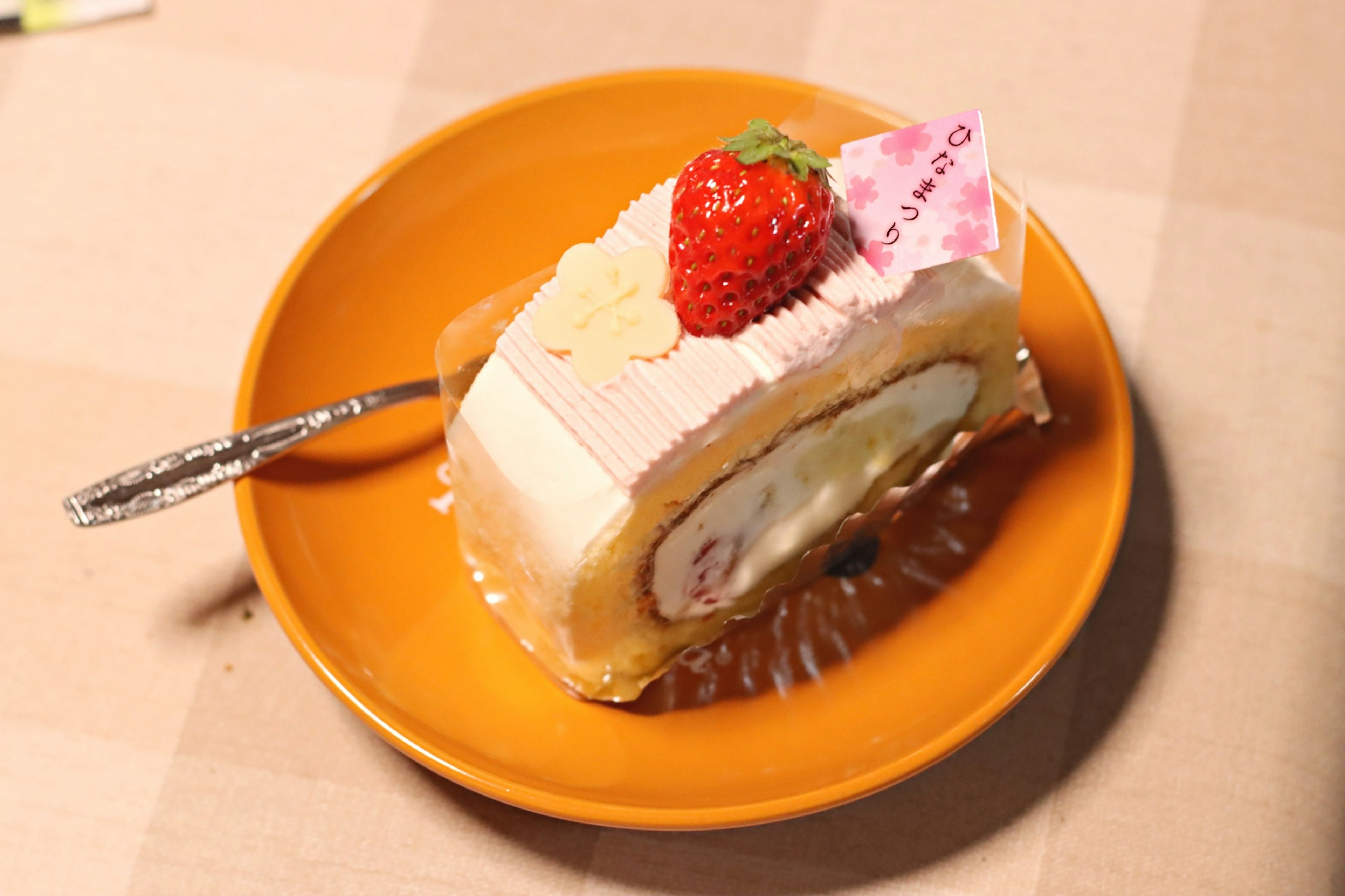 Torta a rotolo alla crema di fragole su un piatto arancione