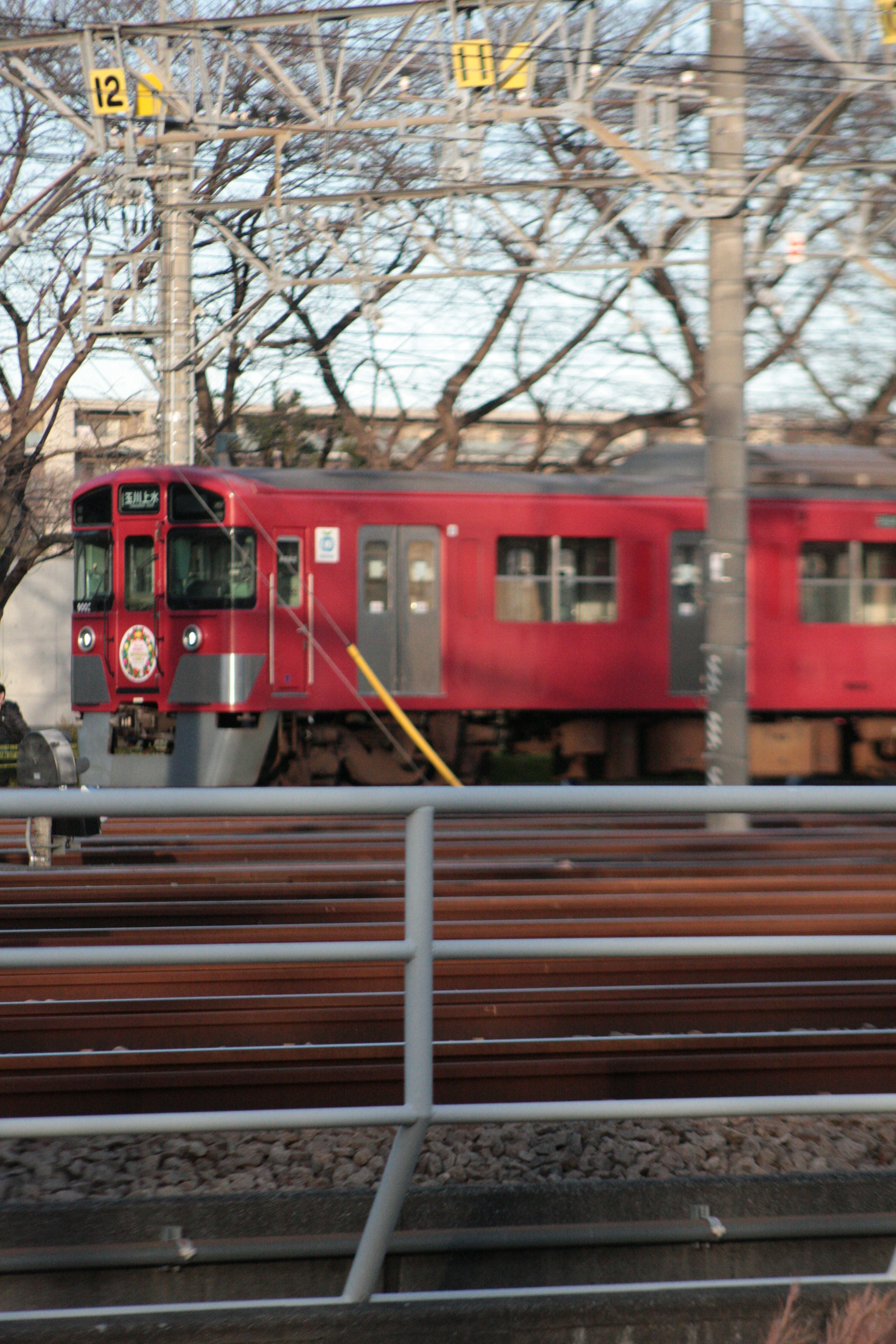 Un train rouge stationné à côté des rails avec une signalisation claire