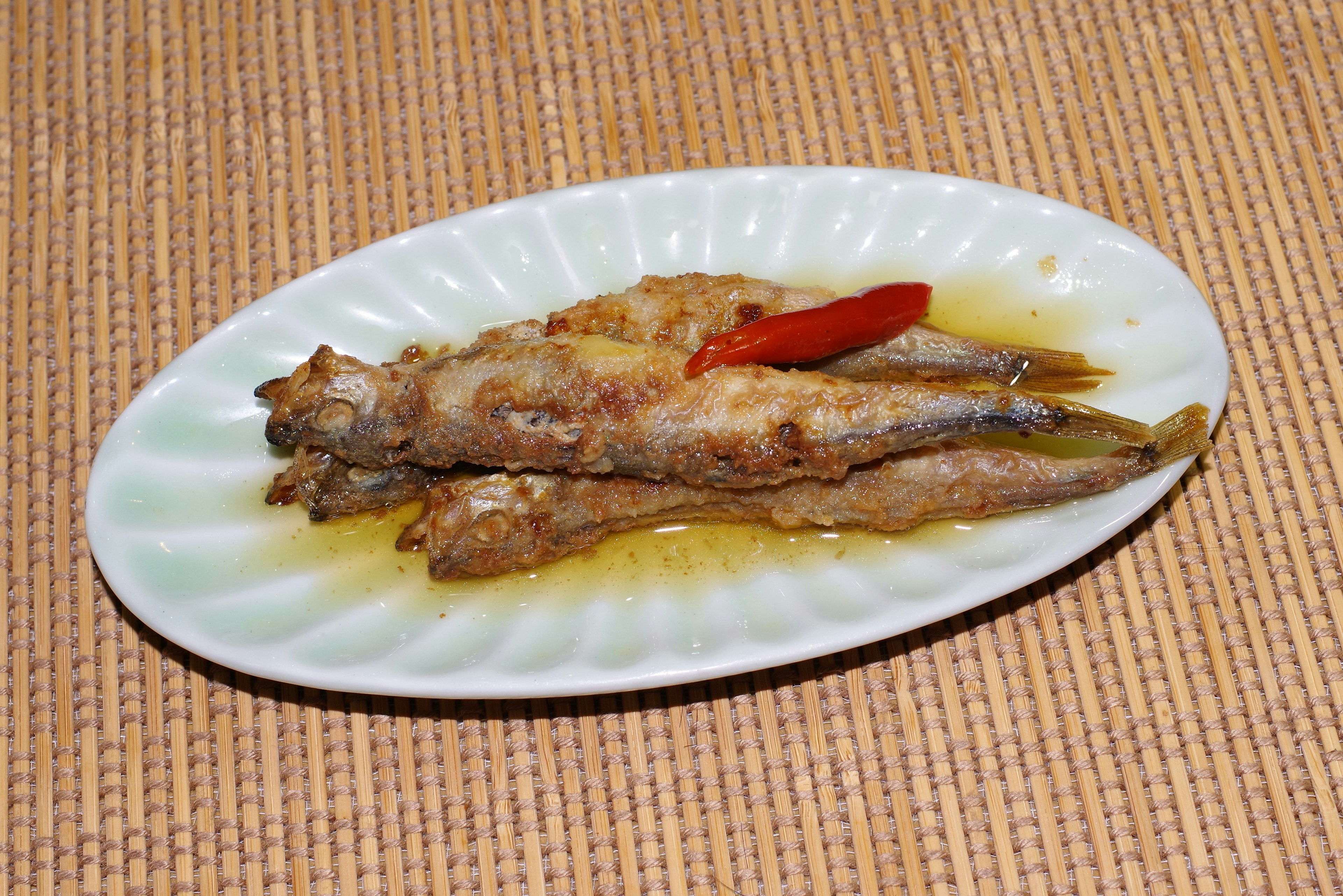 Fried fish dish served on a plate with a red chili pepper