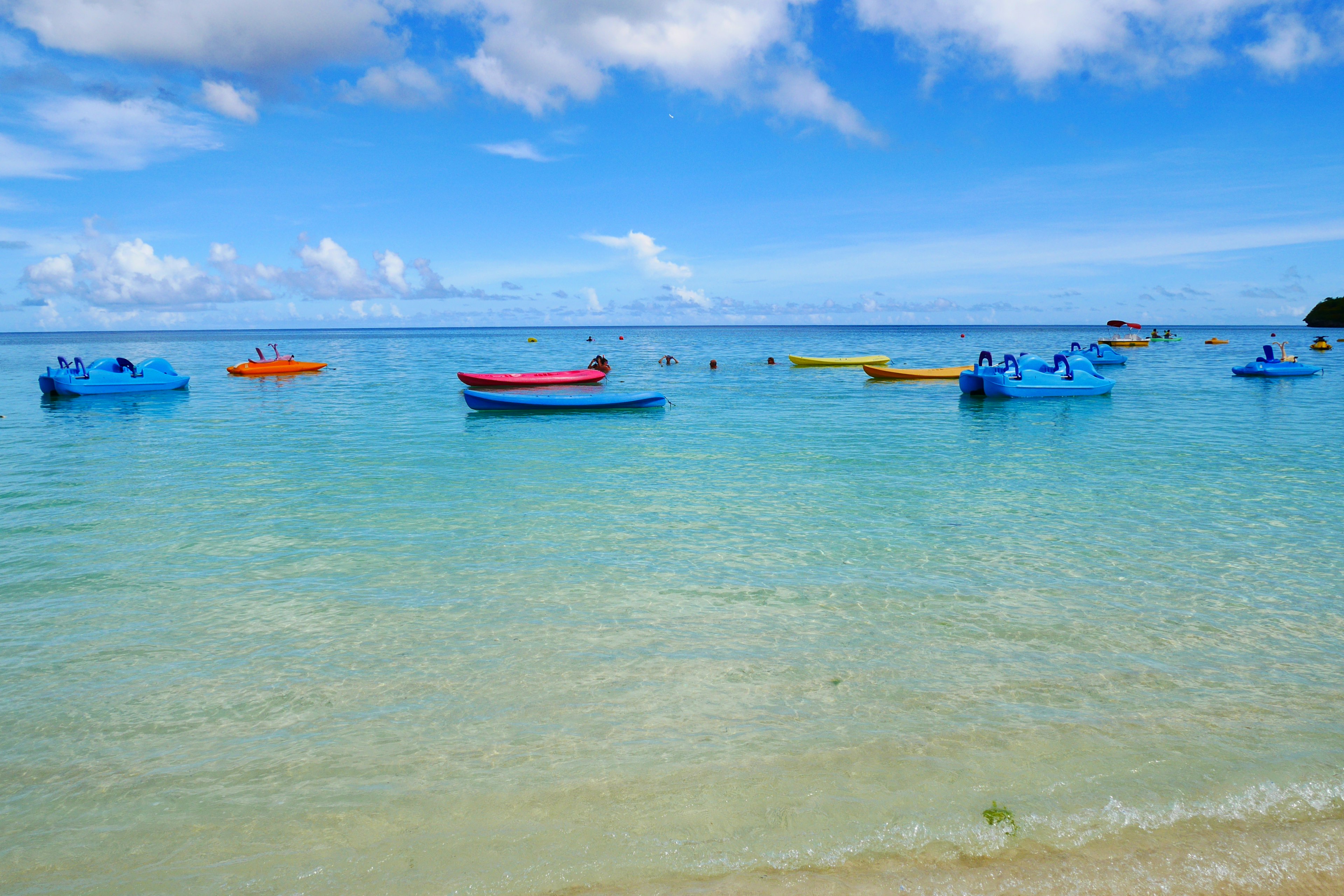 ทิวทัศน์ชายหาดที่สวยงามพร้อมเรือหลากสีลอยอยู่บนผิวน้ำสีฟ้าใส