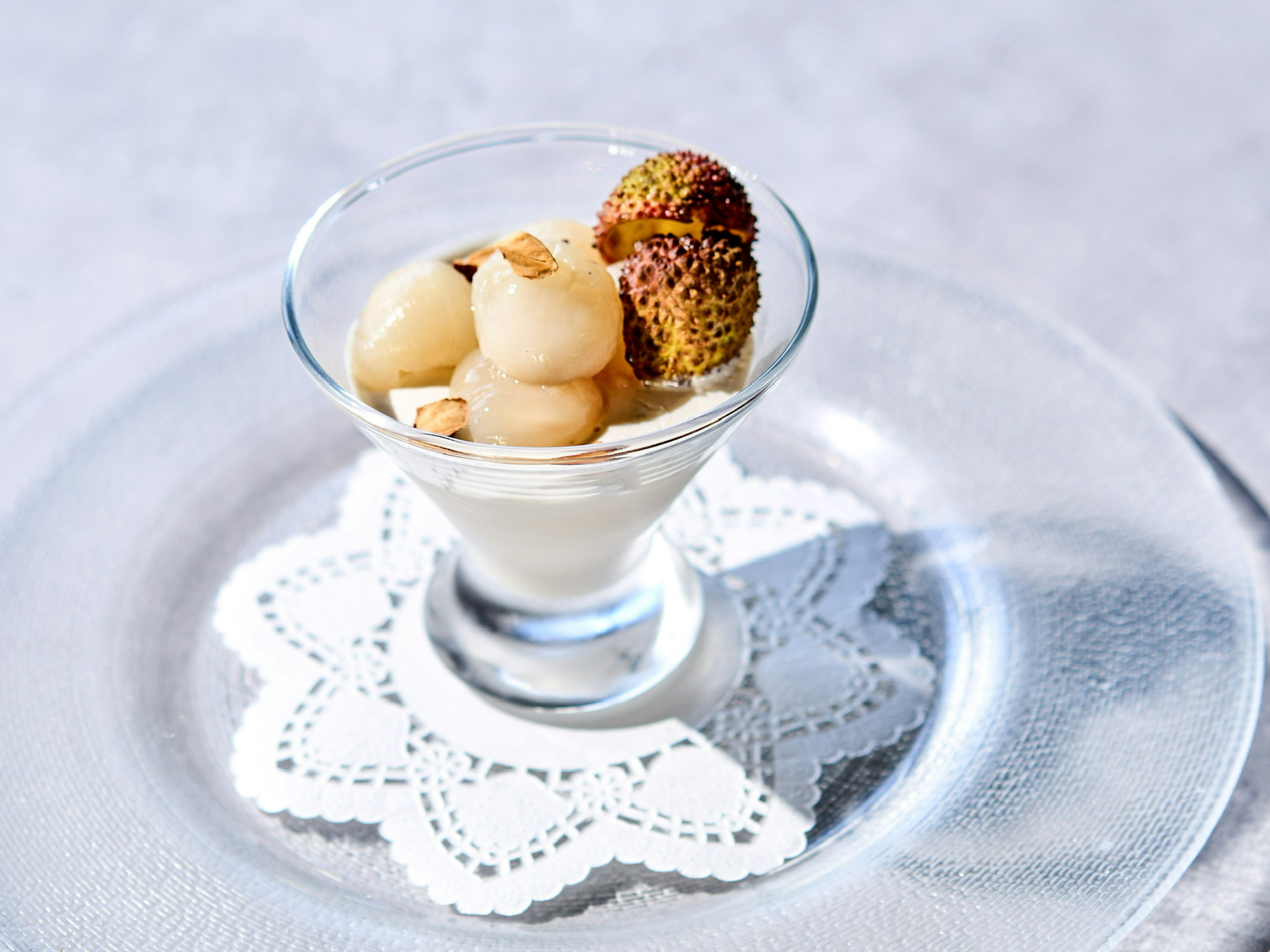 Dessert cremoso guarnito con litchi e longan in una coppa di vetro