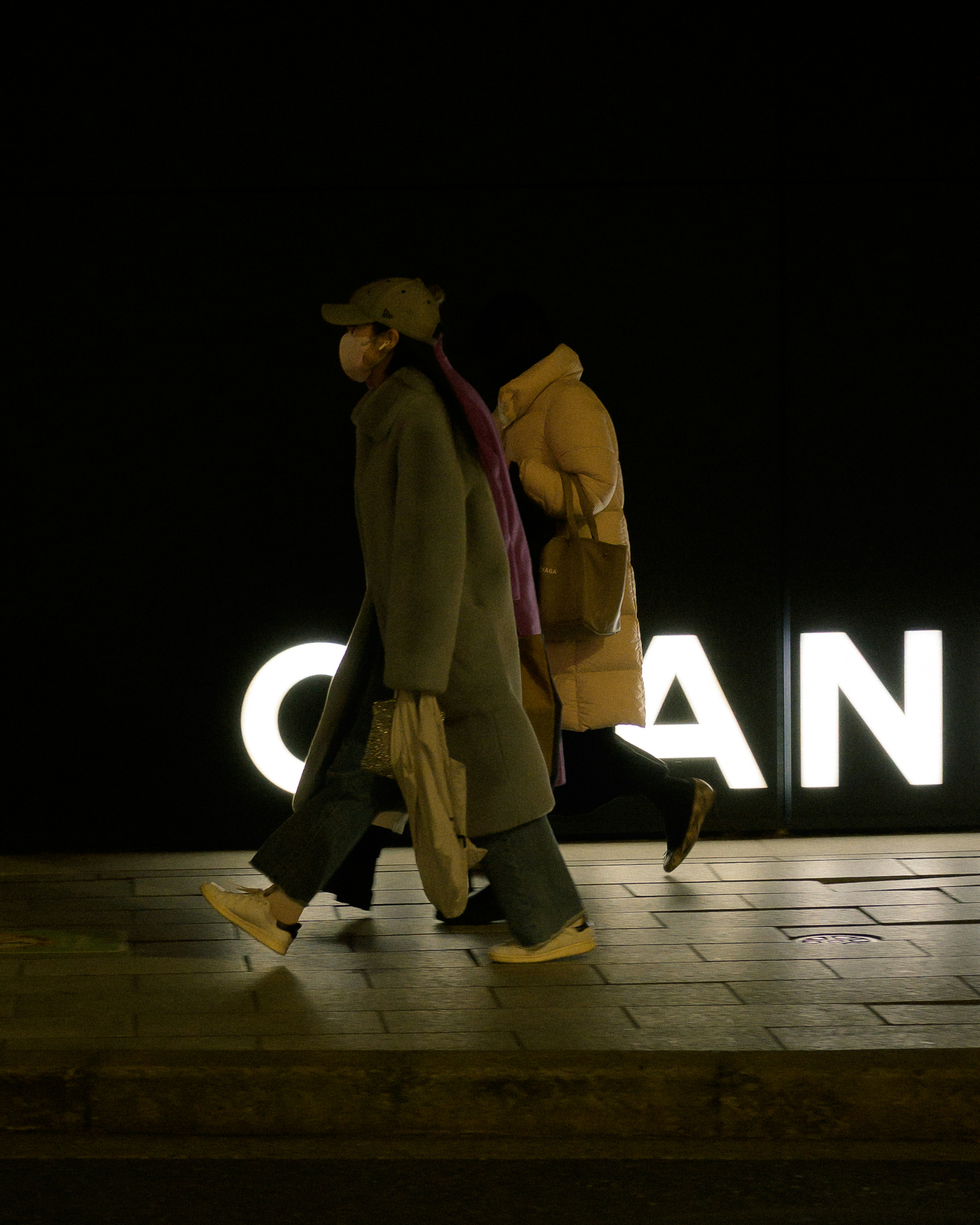 Due persone che camminano su uno sfondo scuro con un grande cartello illuminato