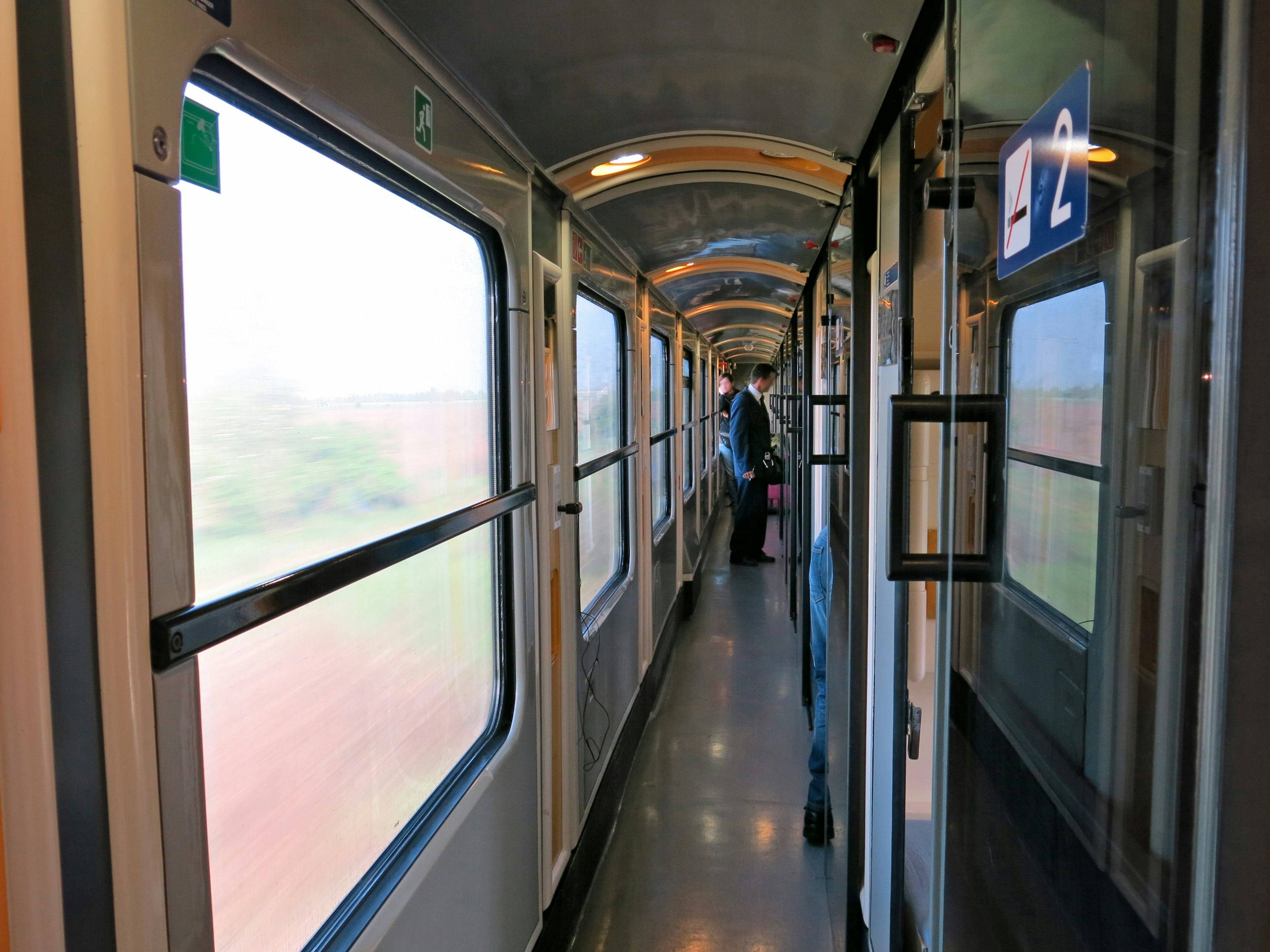 Couloir intérieur d'un train avec des fenêtres et un passager