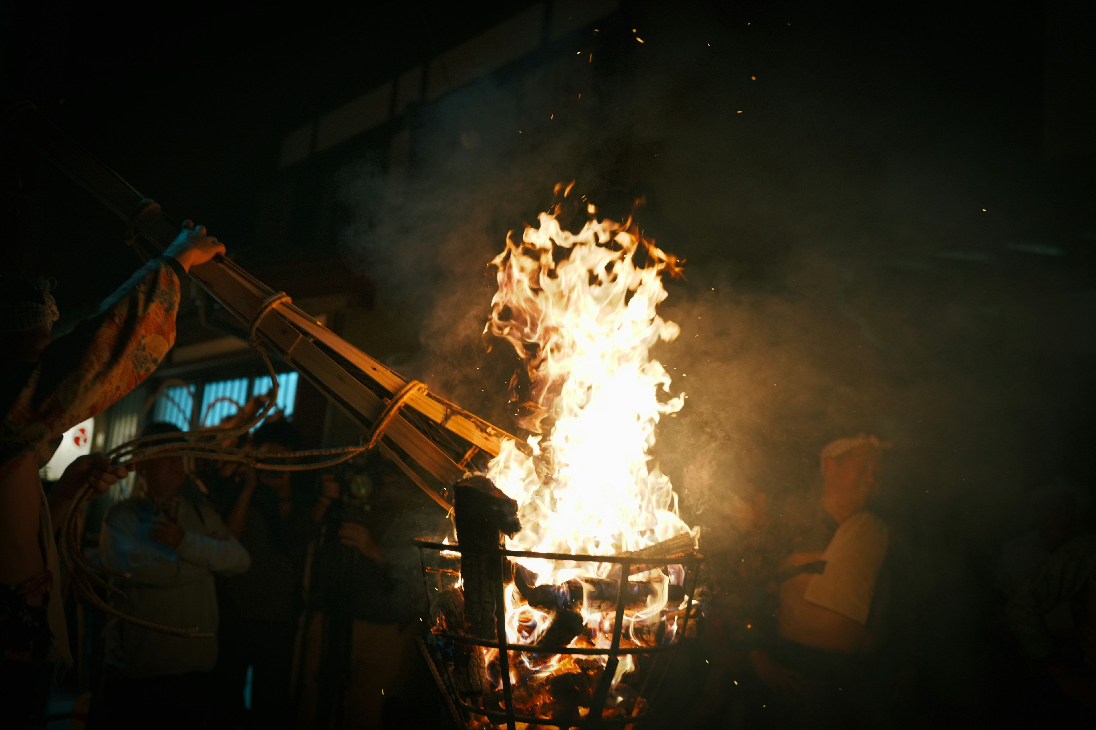 Fiamme che si alzano da una struttura con persone riunite attorno