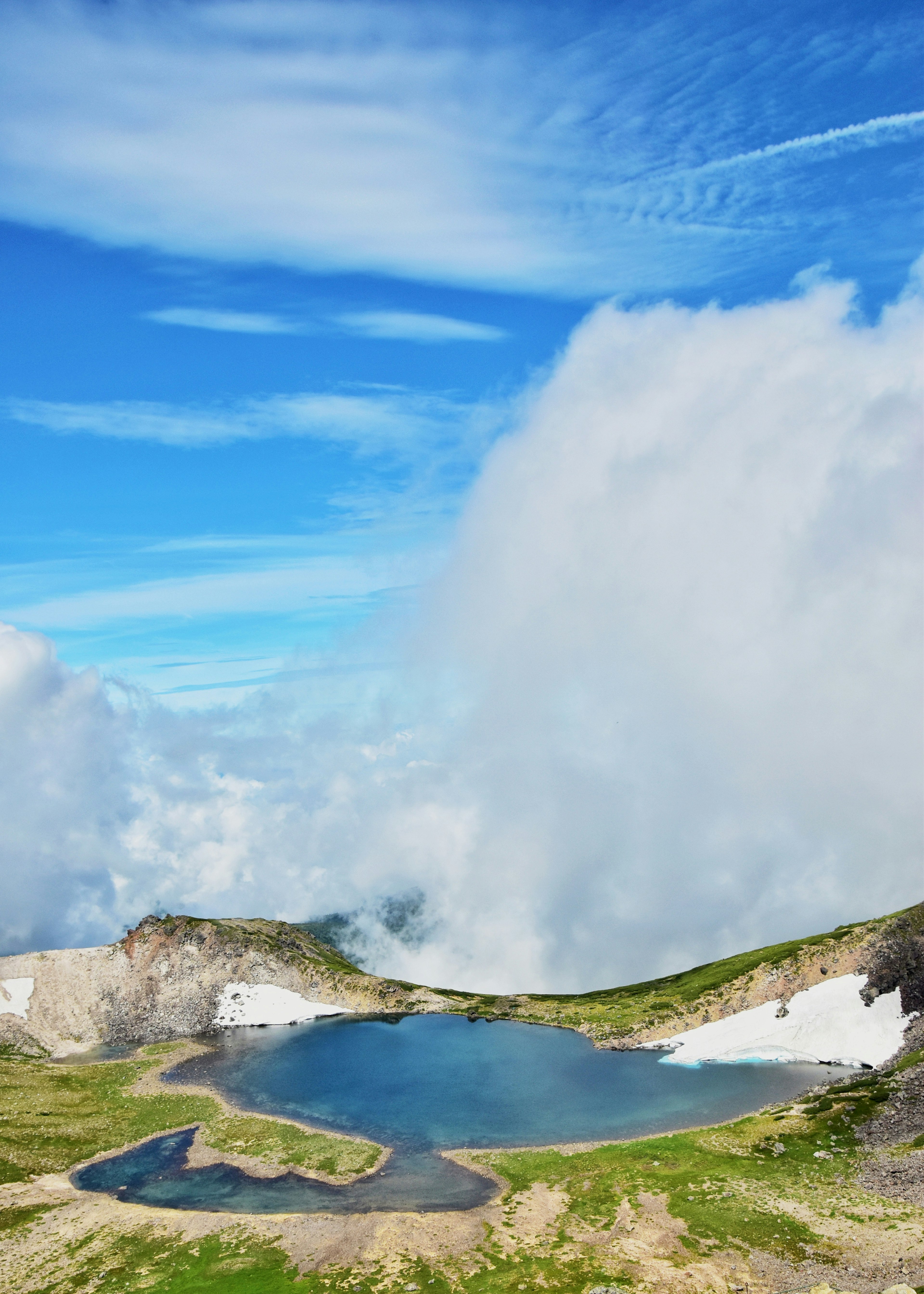 Beau lac au sommet de la montagne entouré d'un ciel bleu et de nuages blancs