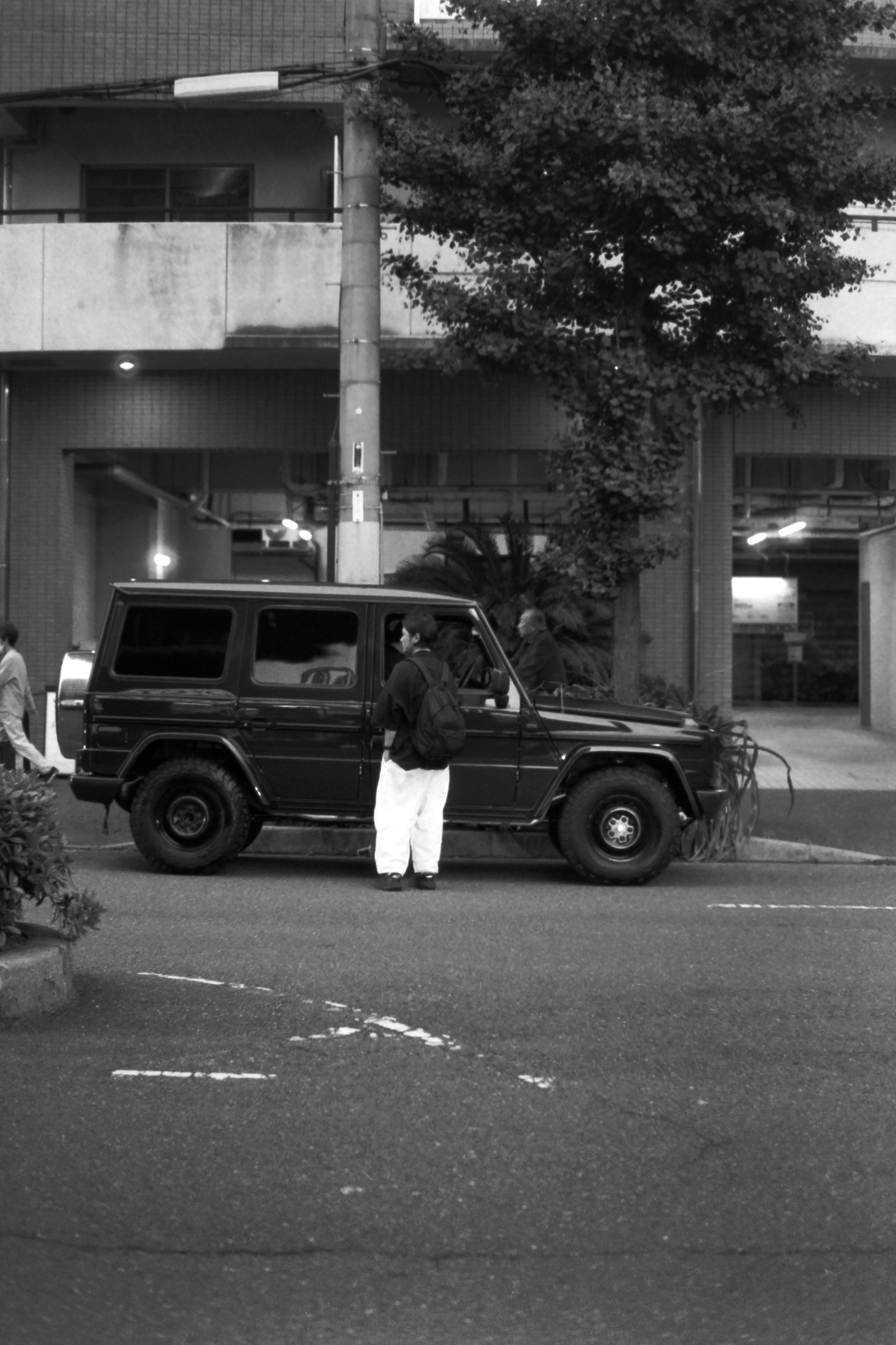 Person standing next to a black SUV in an urban setting