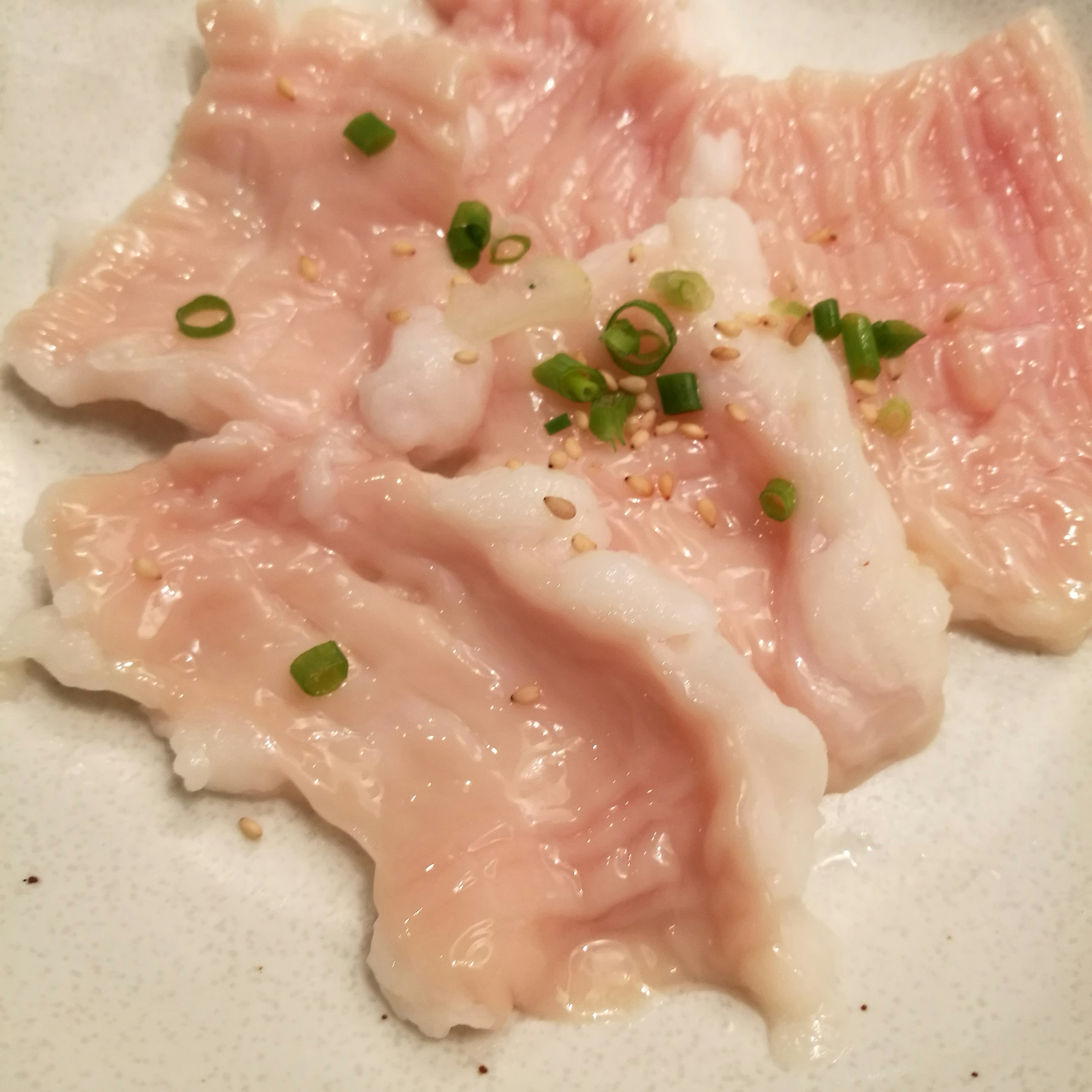 Cerdo en rodajas finas con cebollín picado y sésamo espolvoreado encima