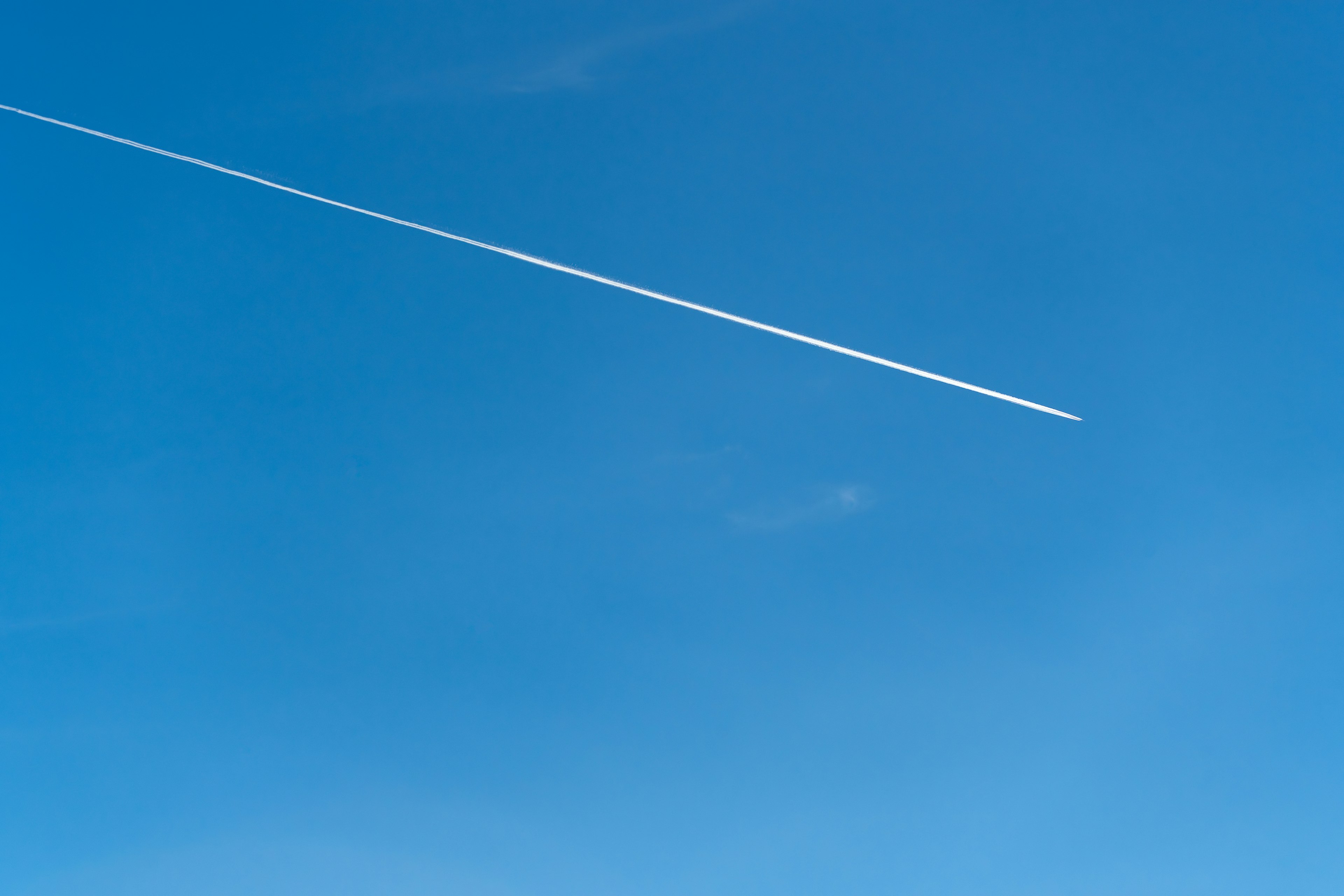 青空に白い飛行機雲が広がる