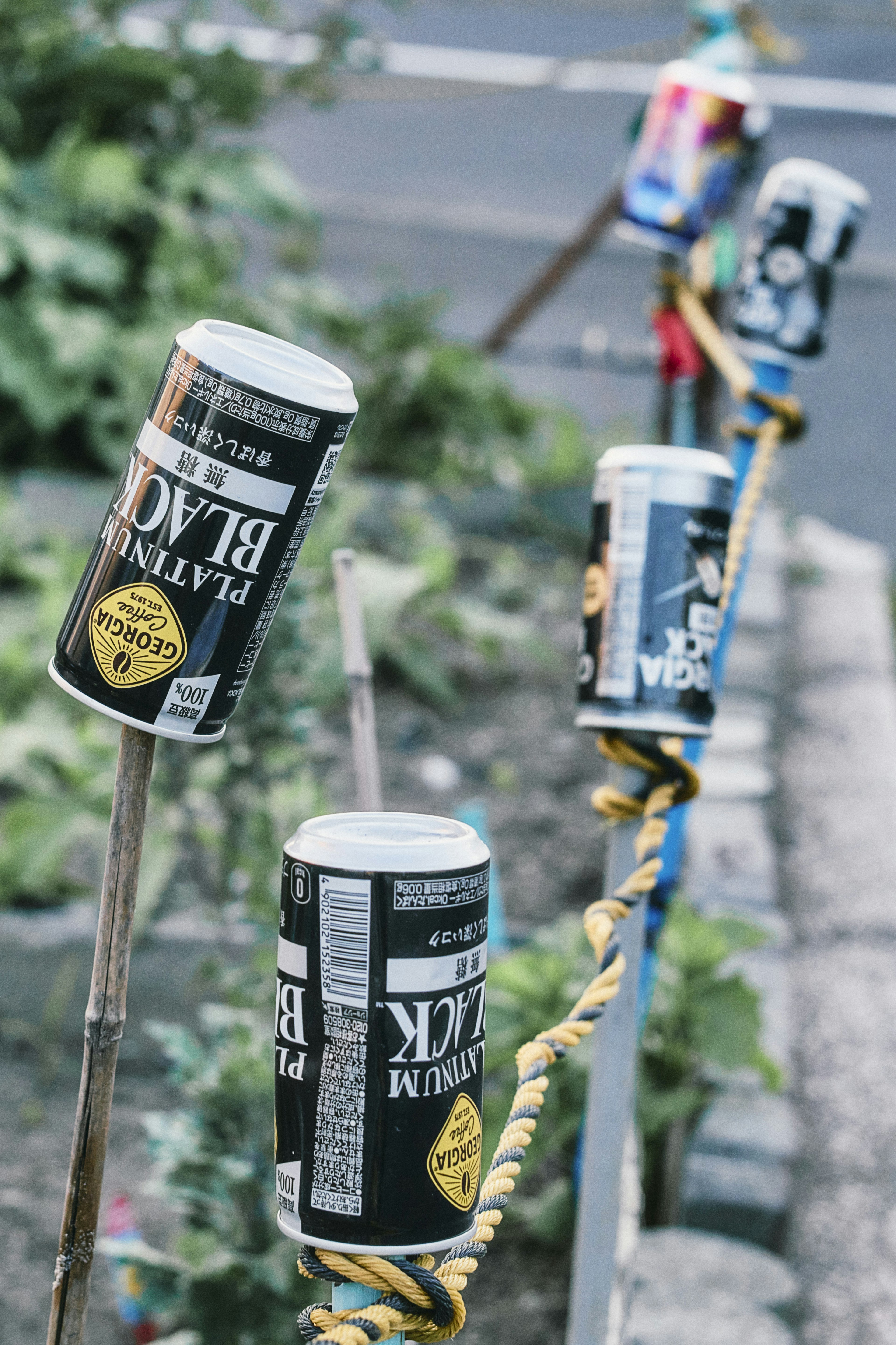 Decoración de jardín única con latas negras dispuestas en palos