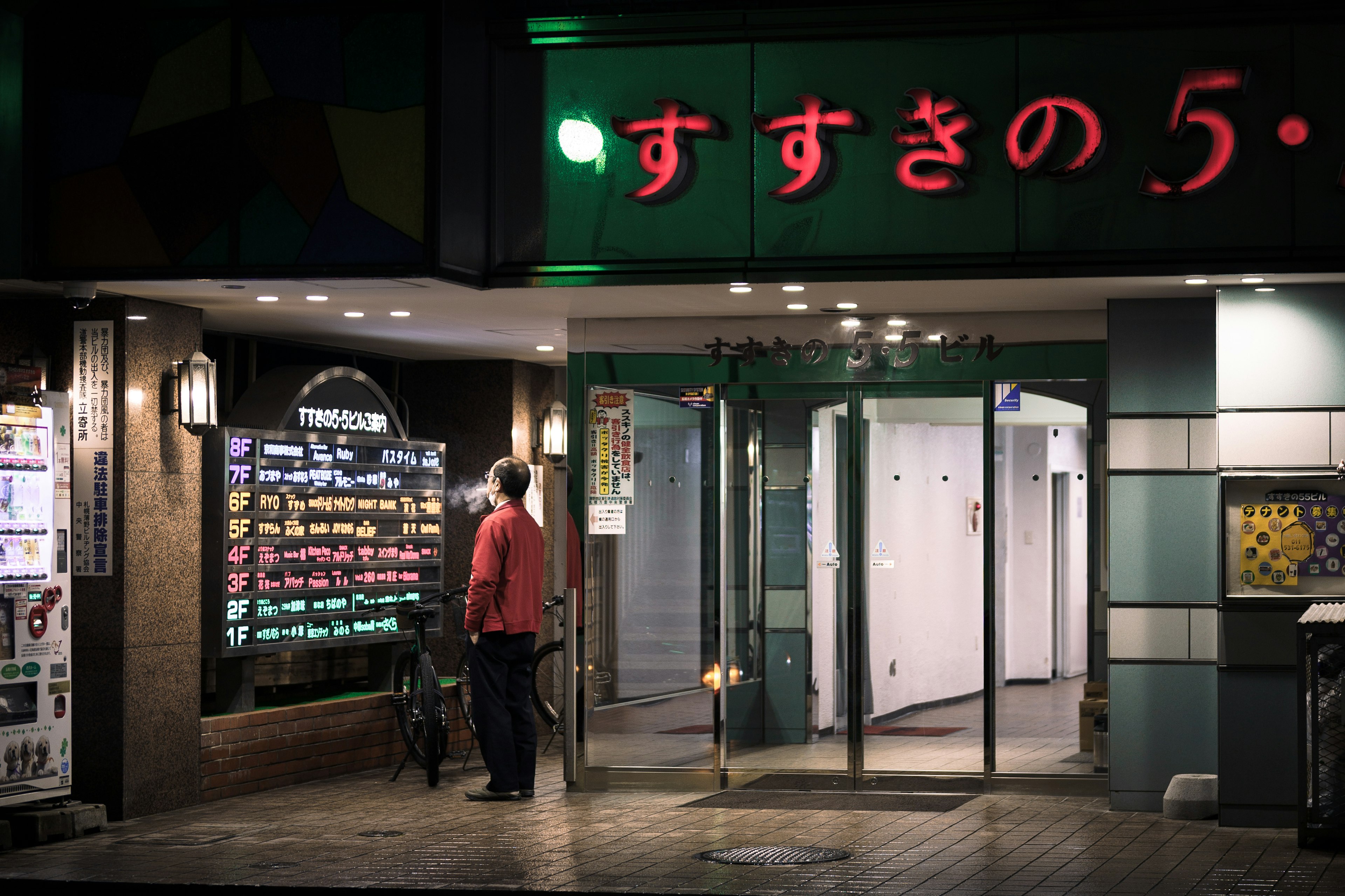 Außenansicht eines japanischen Restaurants mit rotem Neonzeichen ein Mann schaut sich die Speisekarte an