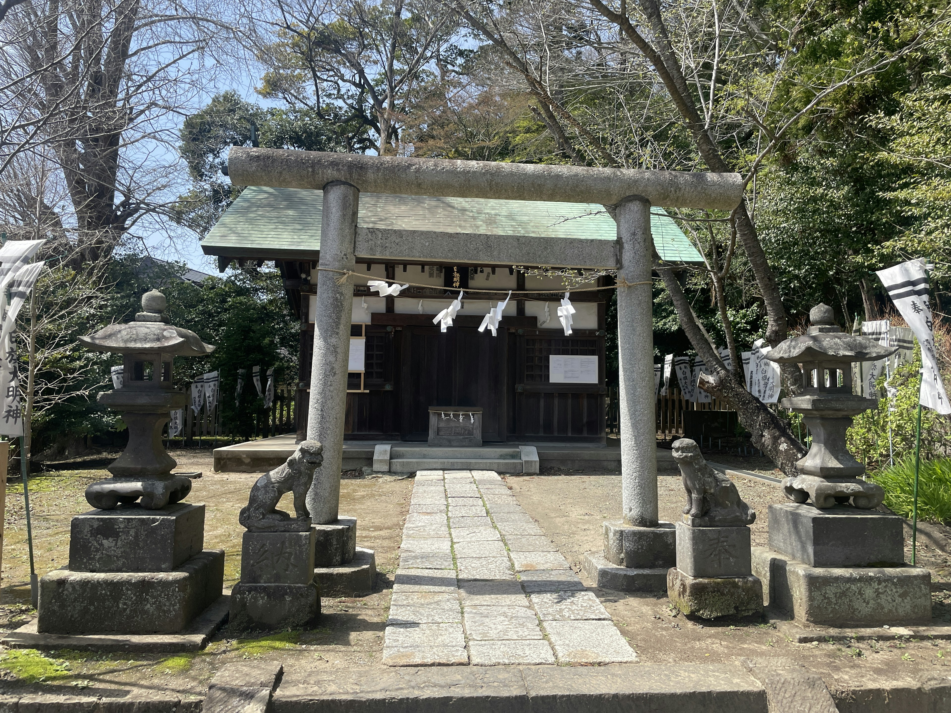 Vista escénica de un santuario con un torii y faroles de piedra en un jardín exuberante