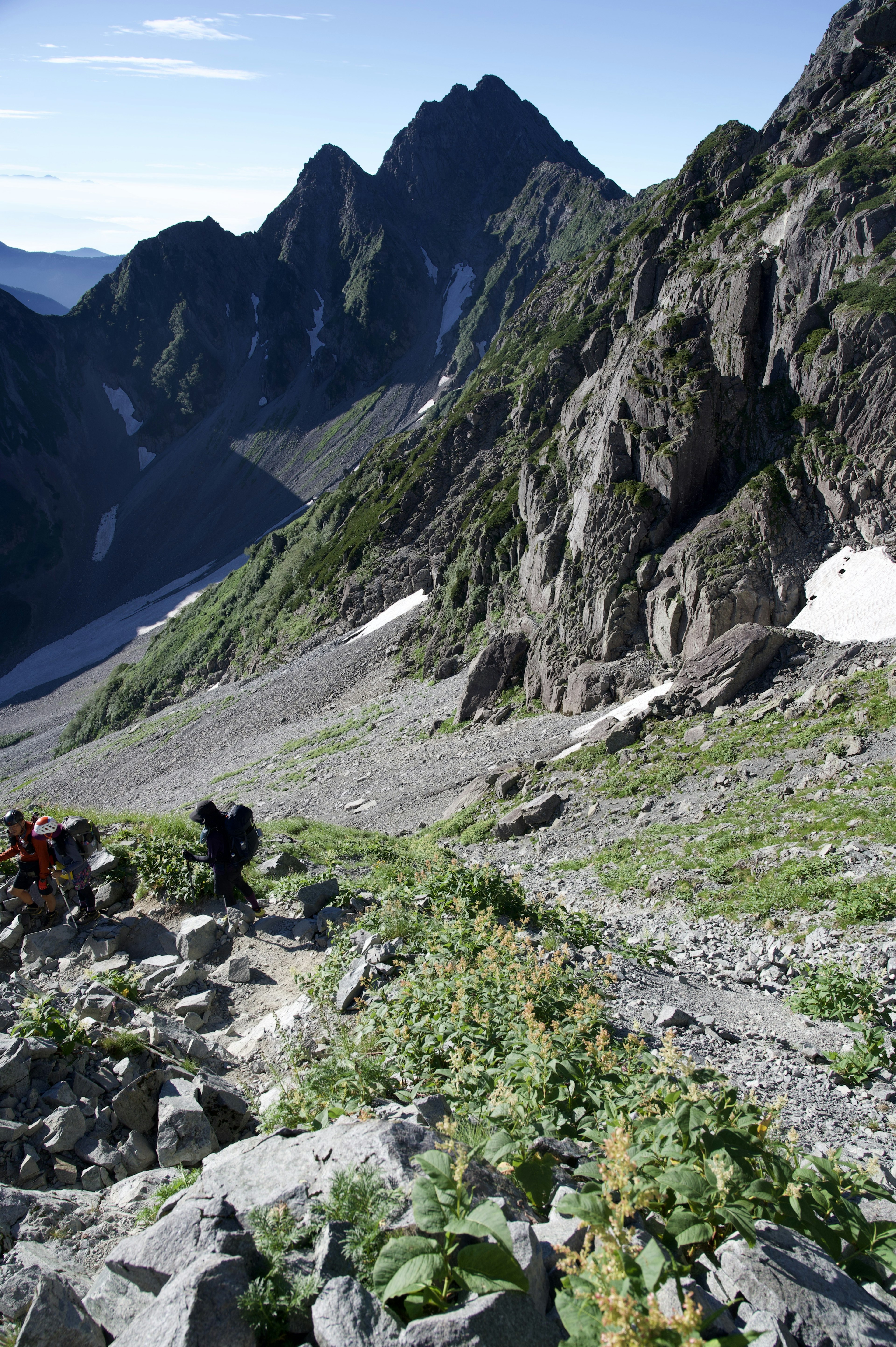 Escursionisti che salgono un sentiero di montagna accidentato con picchi maestosi