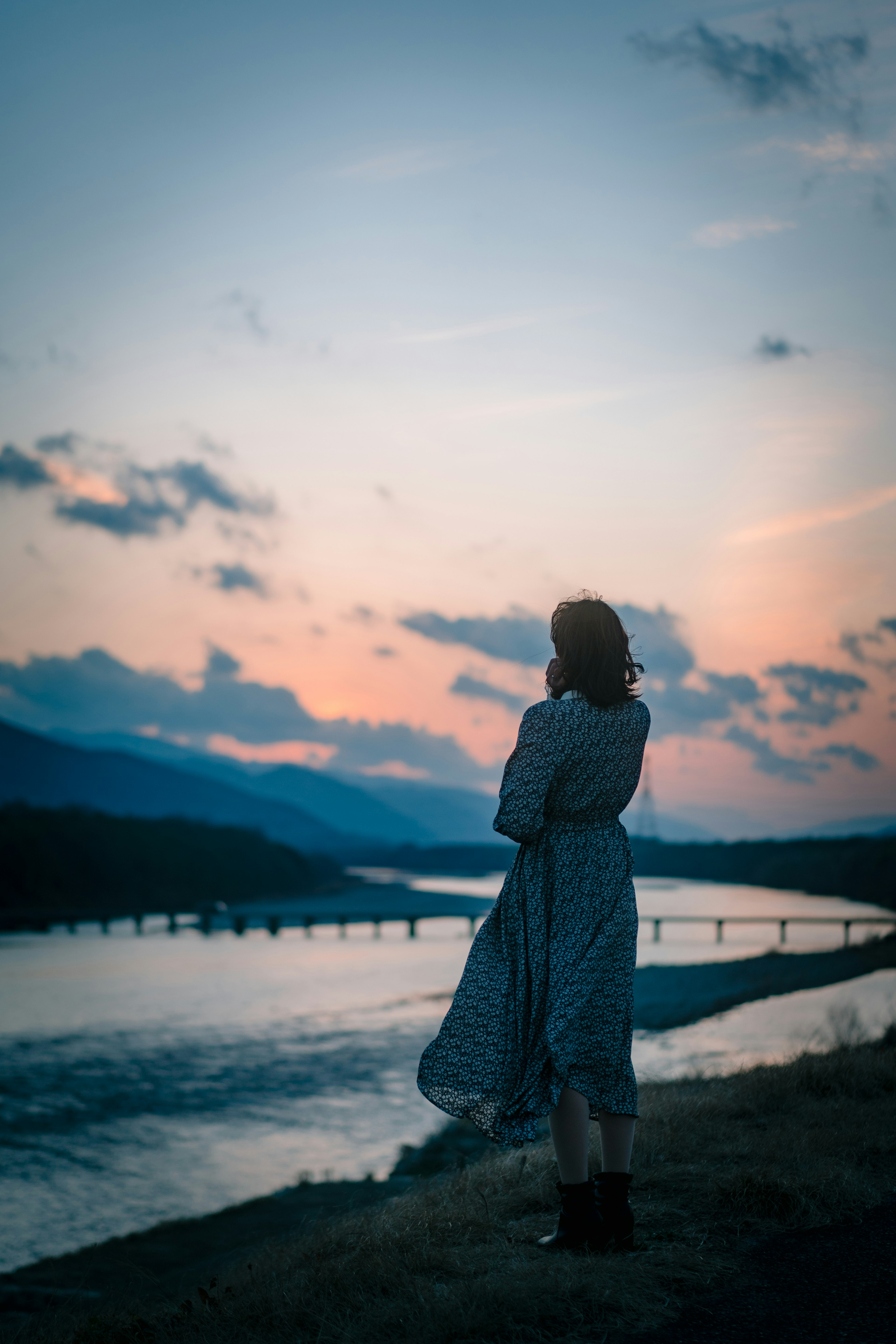 Silhouette d'une femme surplombant une rivière au coucher du soleil