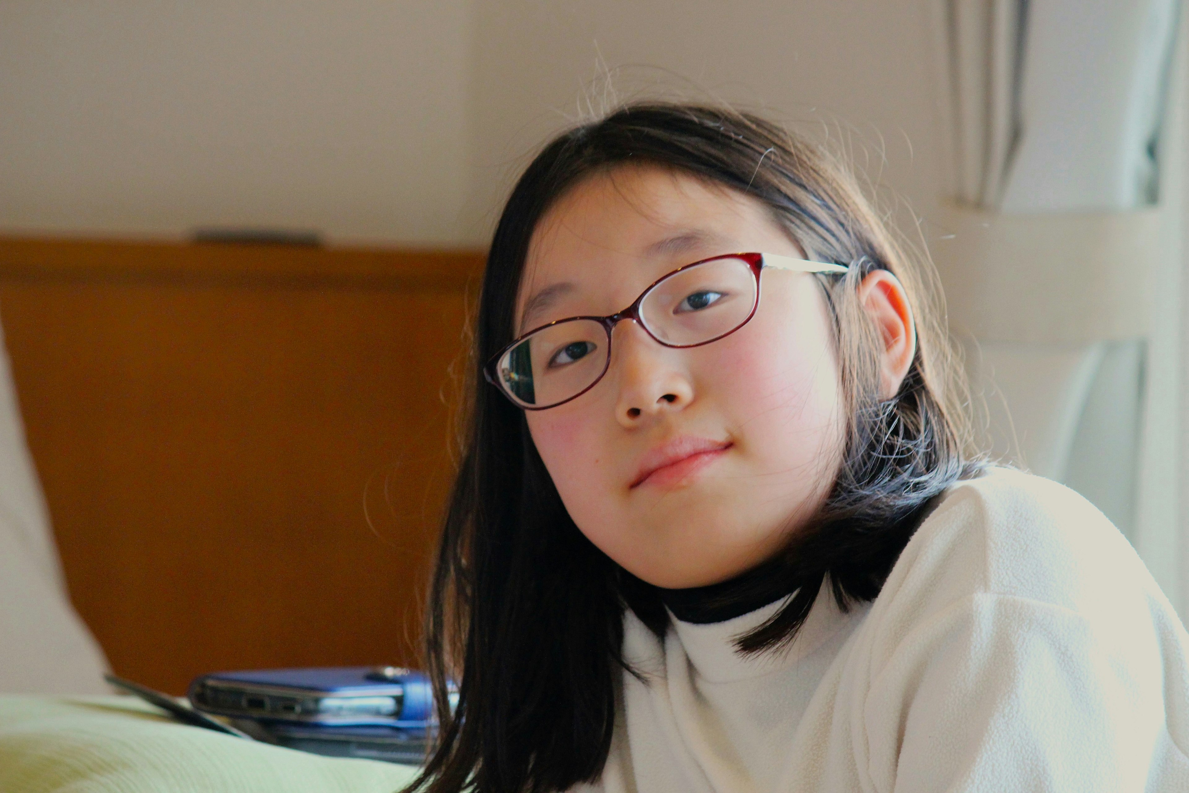 Une fille portant des lunettes souriant dans un cadre intérieur