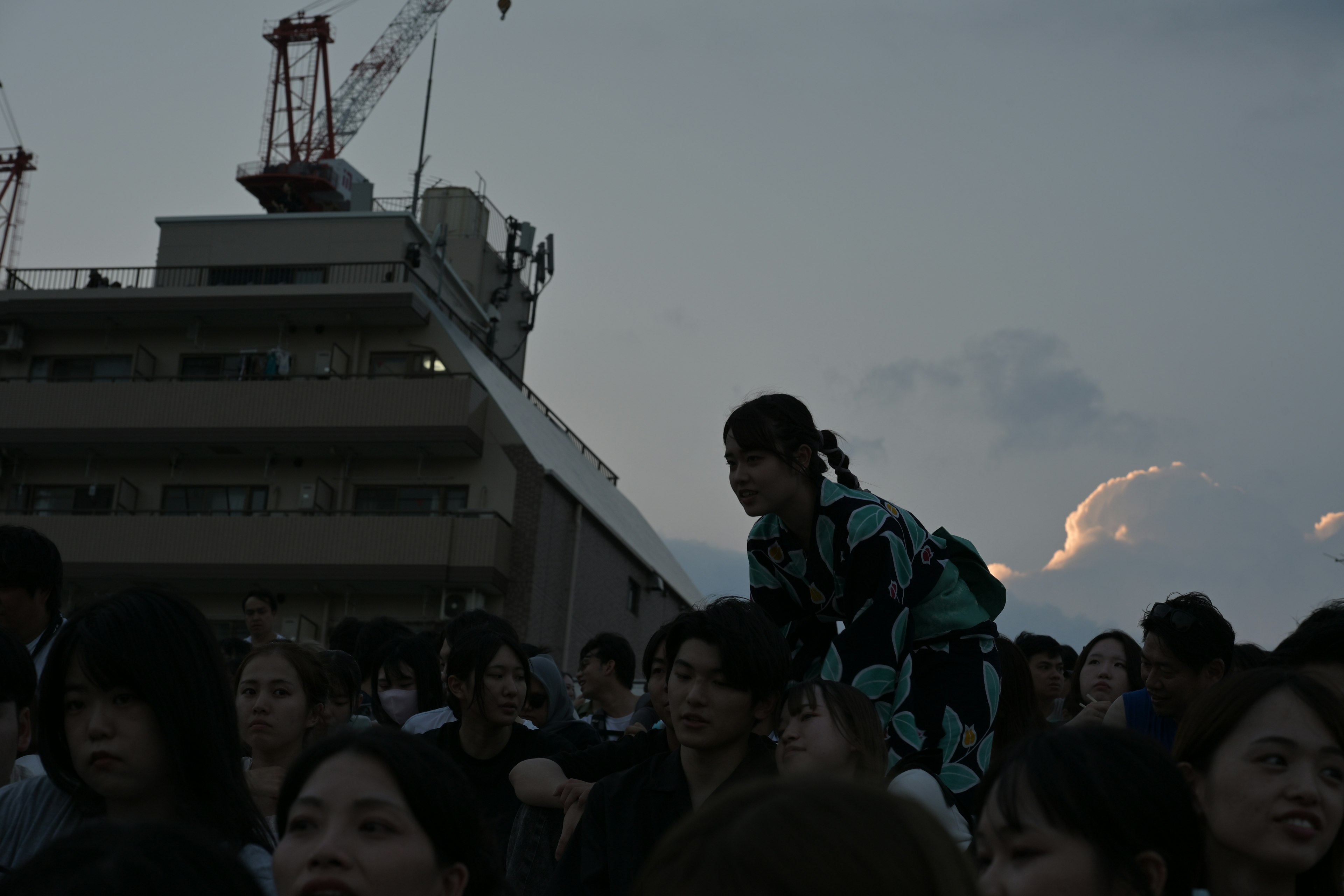 Una escena al atardecer con una mujer en kimono de pie entre una multitud