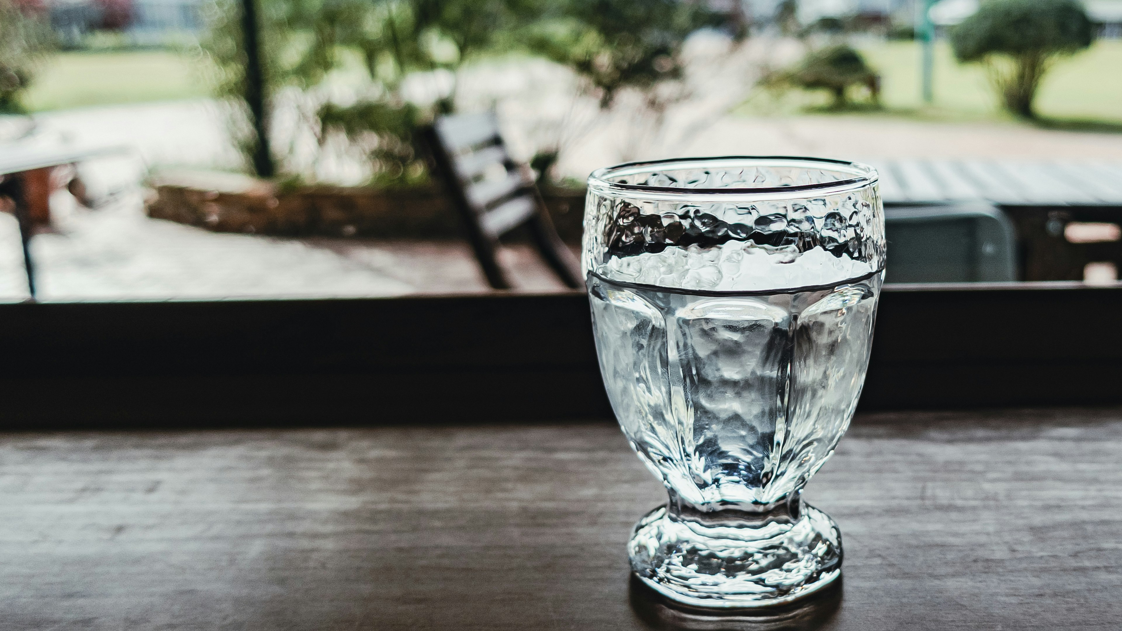 Decorative glass filled with water on a wooden table with a green background