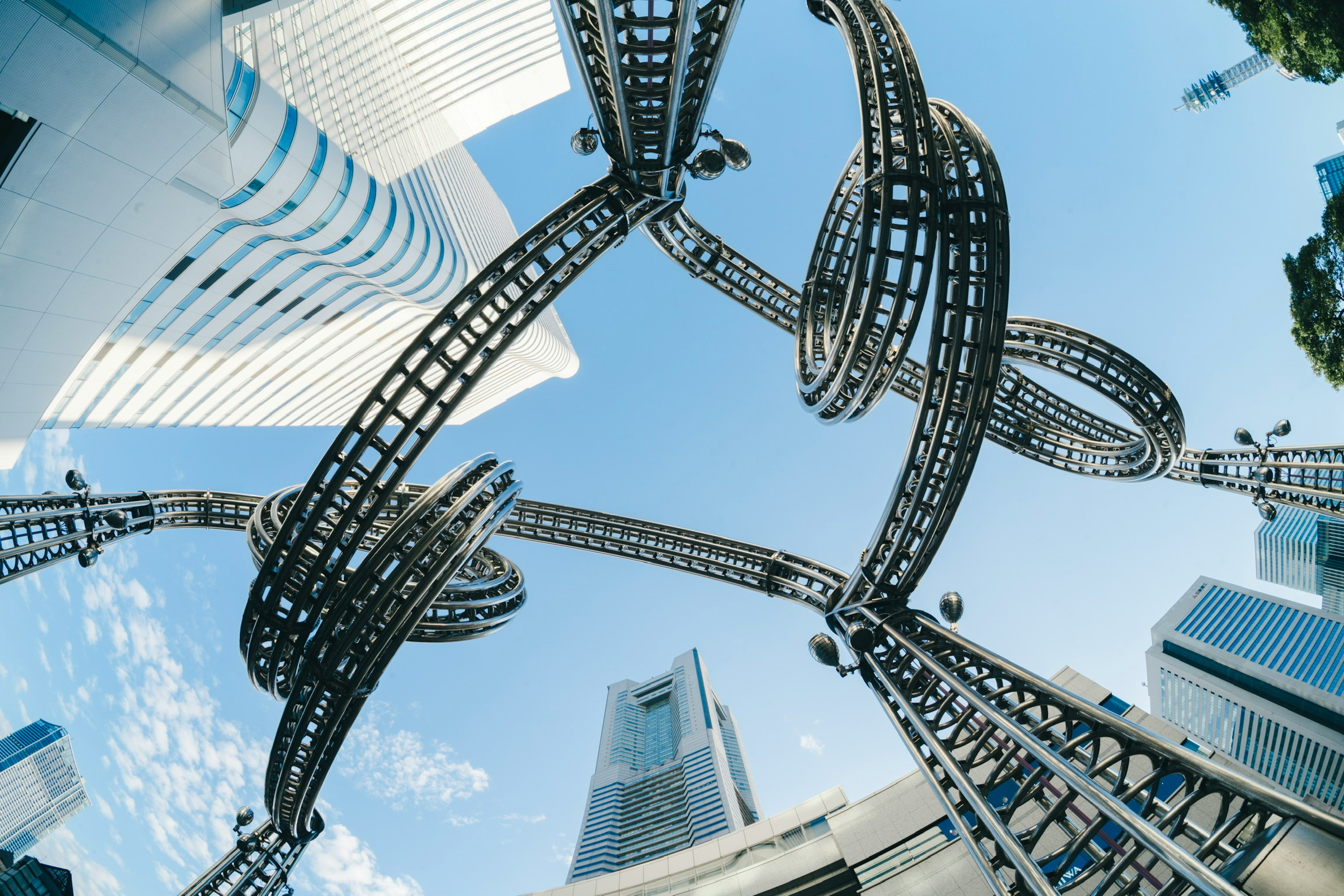 Unique metal structure with loops against a backdrop of buildings and blue sky