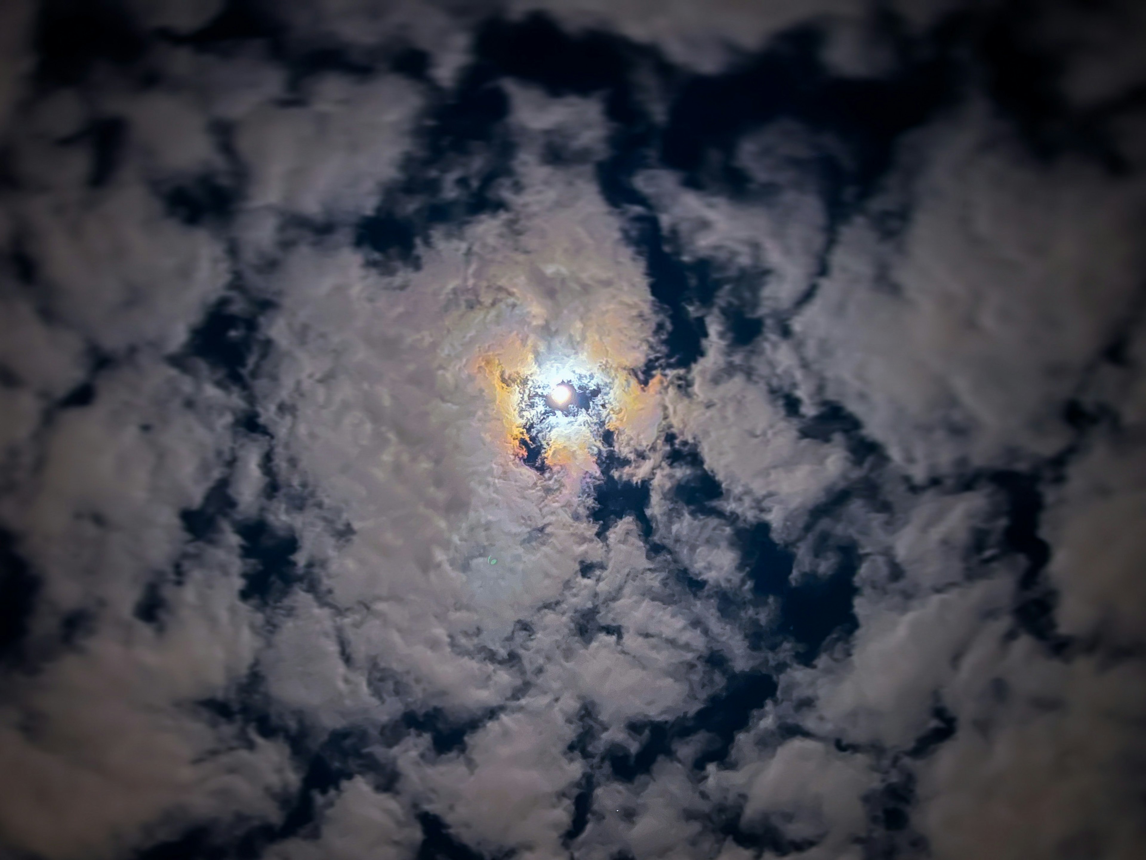 A bright sun surrounded by swirling clouds in a dark blue sky