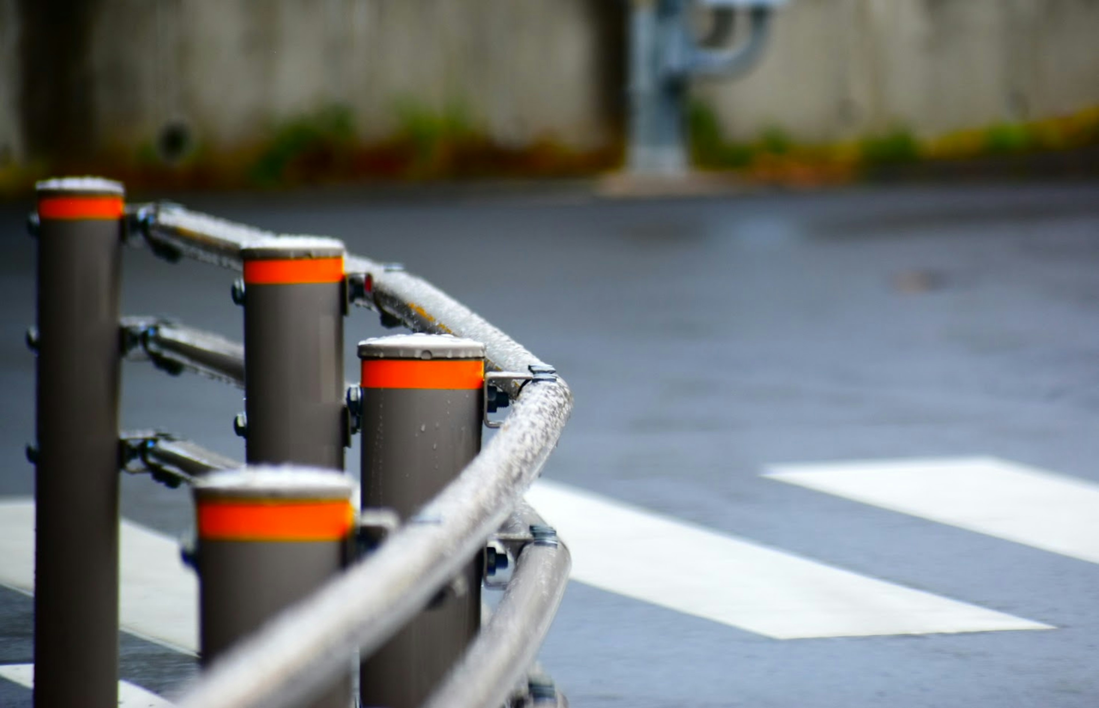 Graue Geländer mit orangefarbenen Kappen und weißem Zebrastreifen im Vordergrund