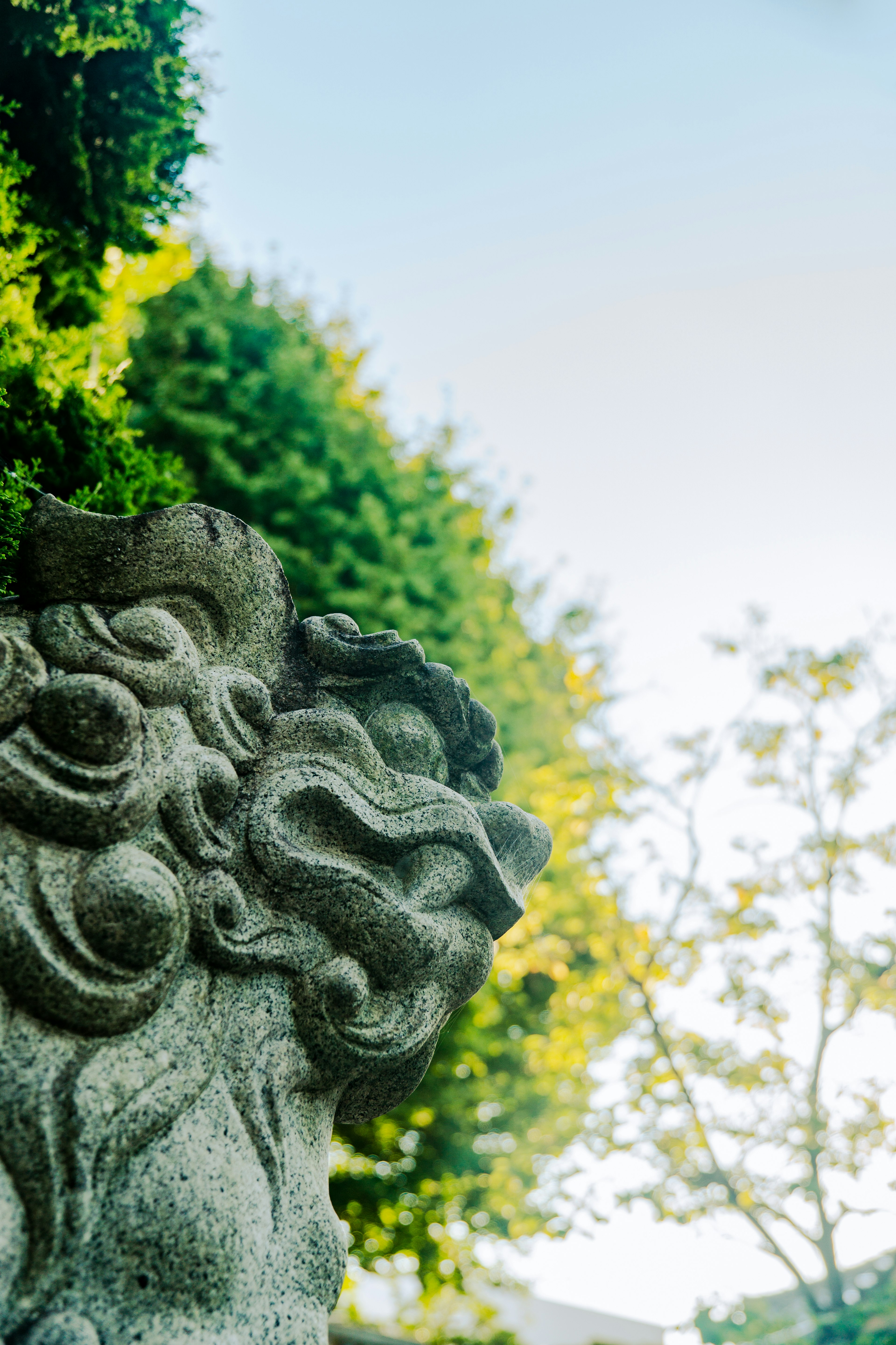 Statua di leone scolpita con fogliame verde sullo sfondo