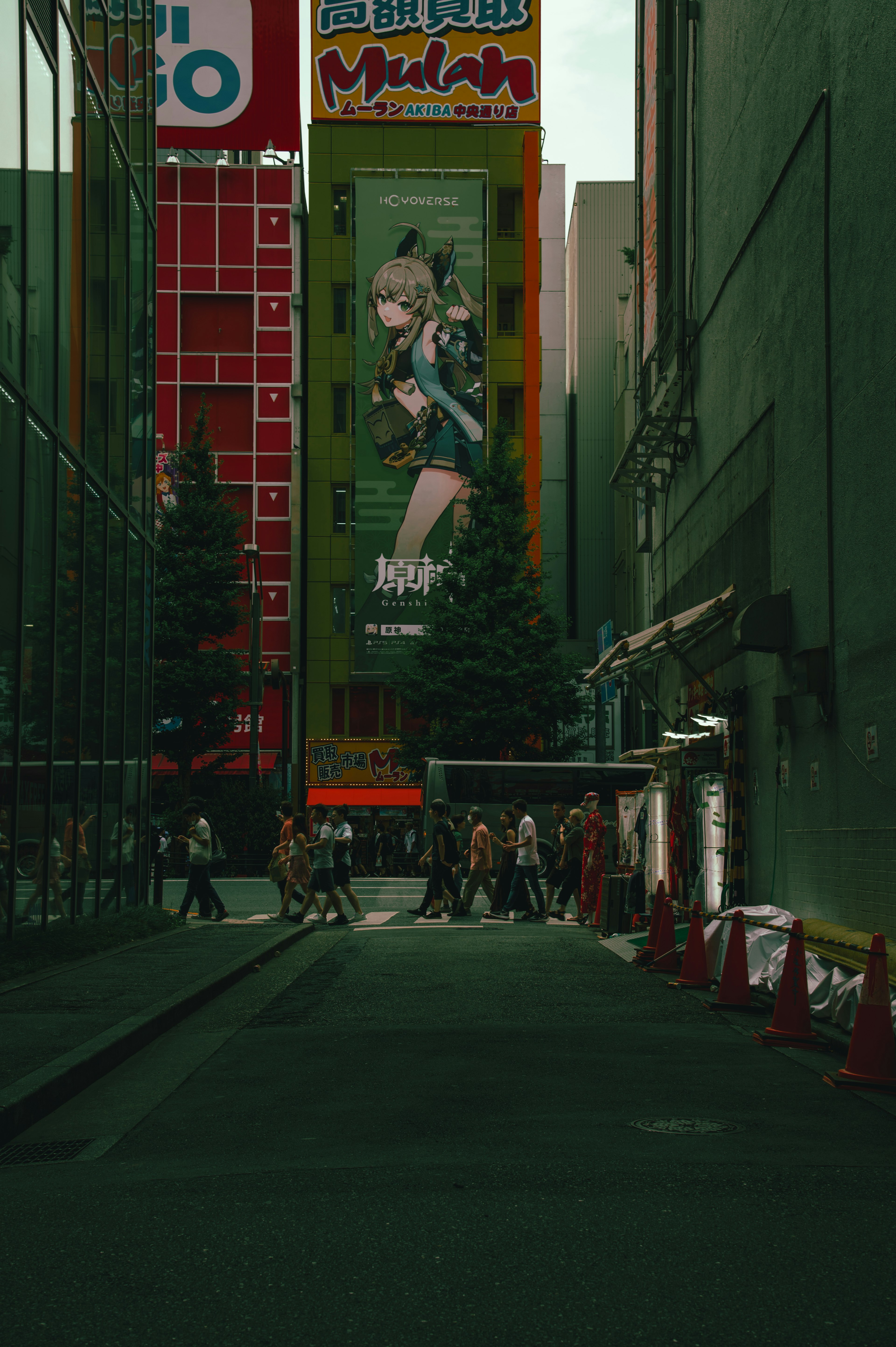 A busy street scene with a large advertisement on a green wall and pedestrians