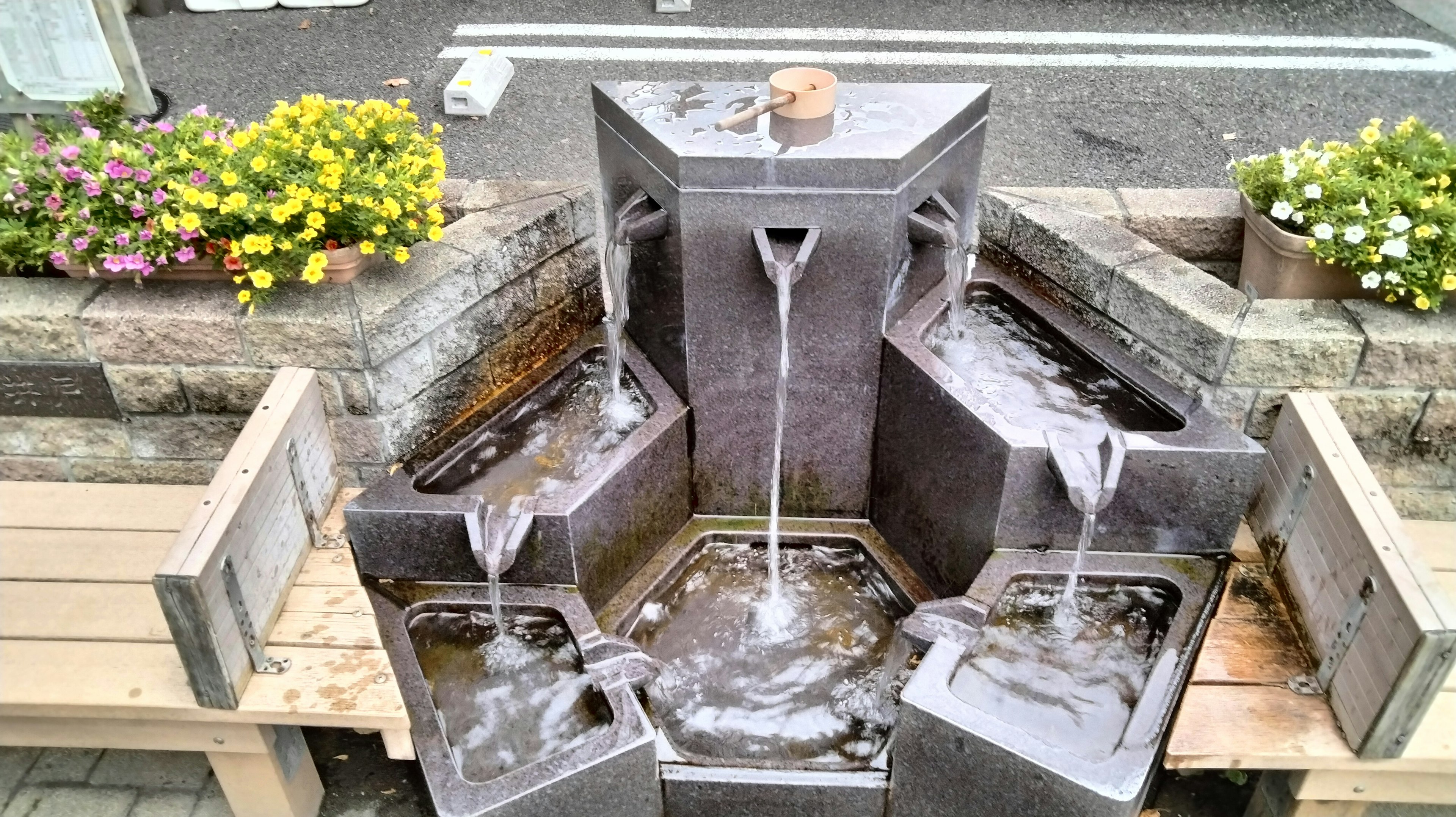 水の流れるモダンな噴水周辺に花が咲いている