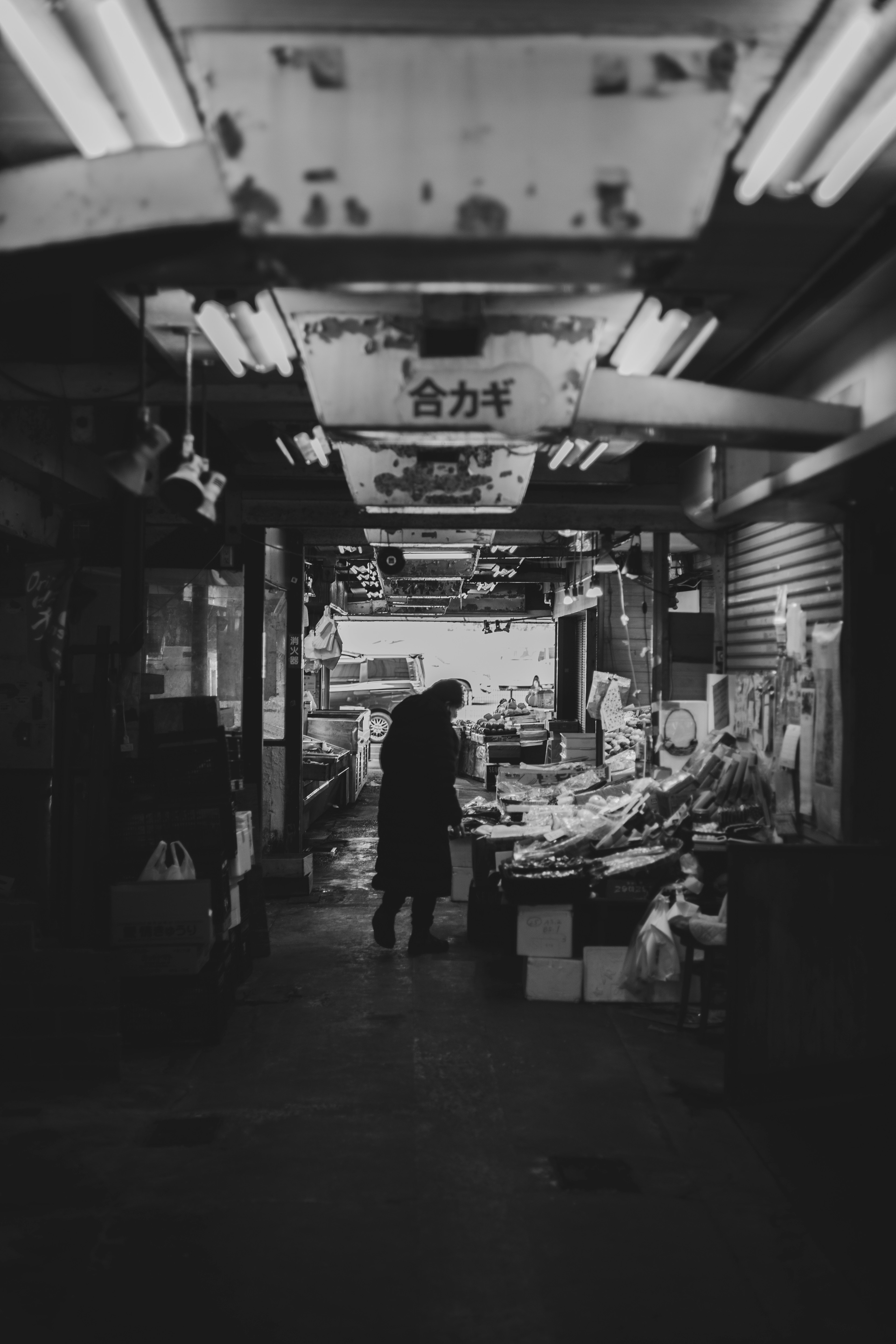 Narrow market alley with a person and displayed goods