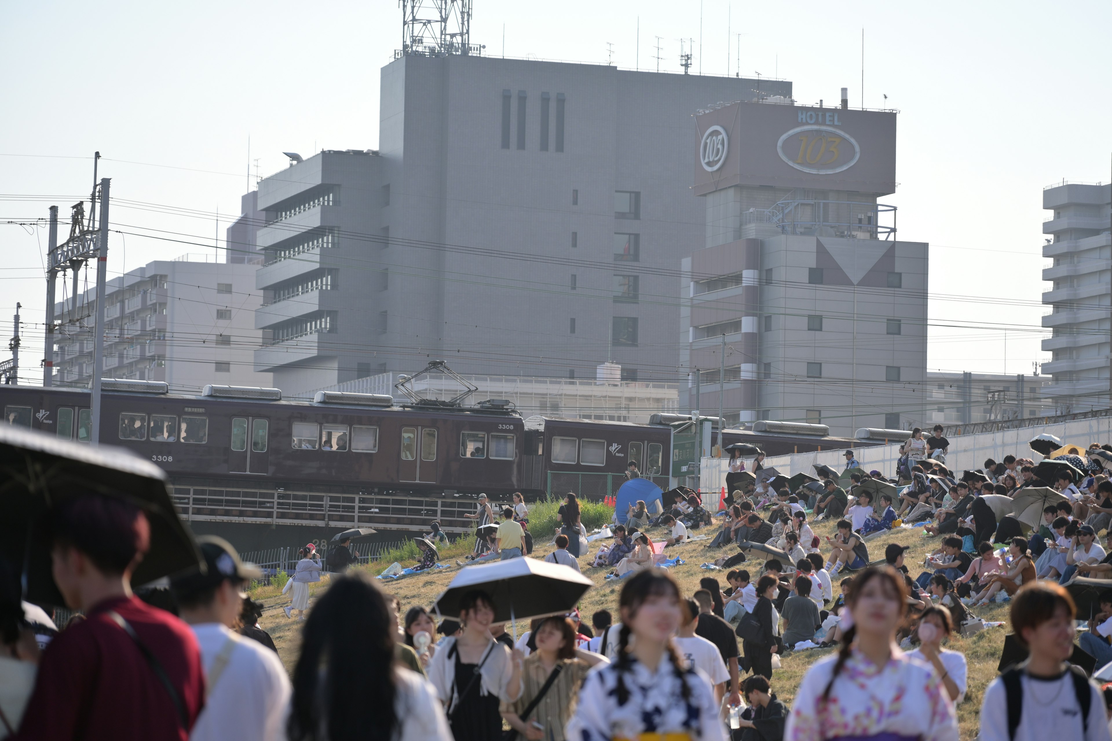 Crowded scene with people gathering near a stationary train in an urban setting