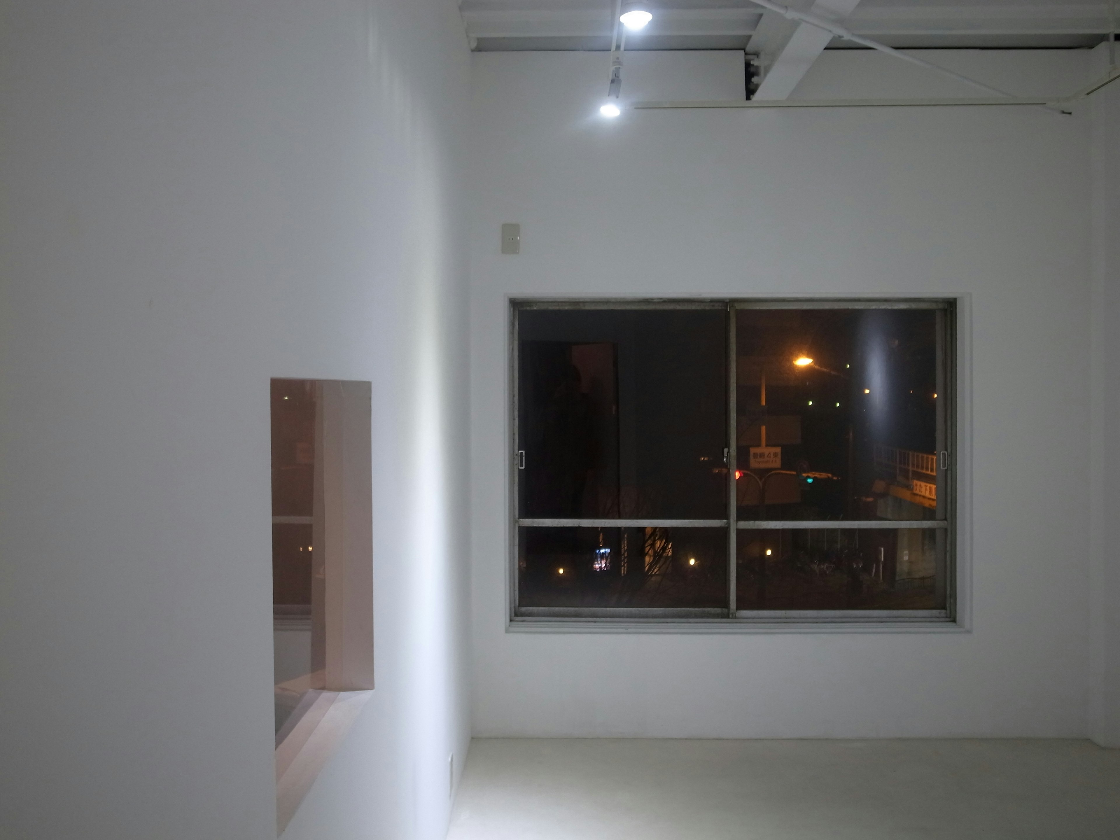 Interior of a bright room with white walls and a window showcasing city lights at night