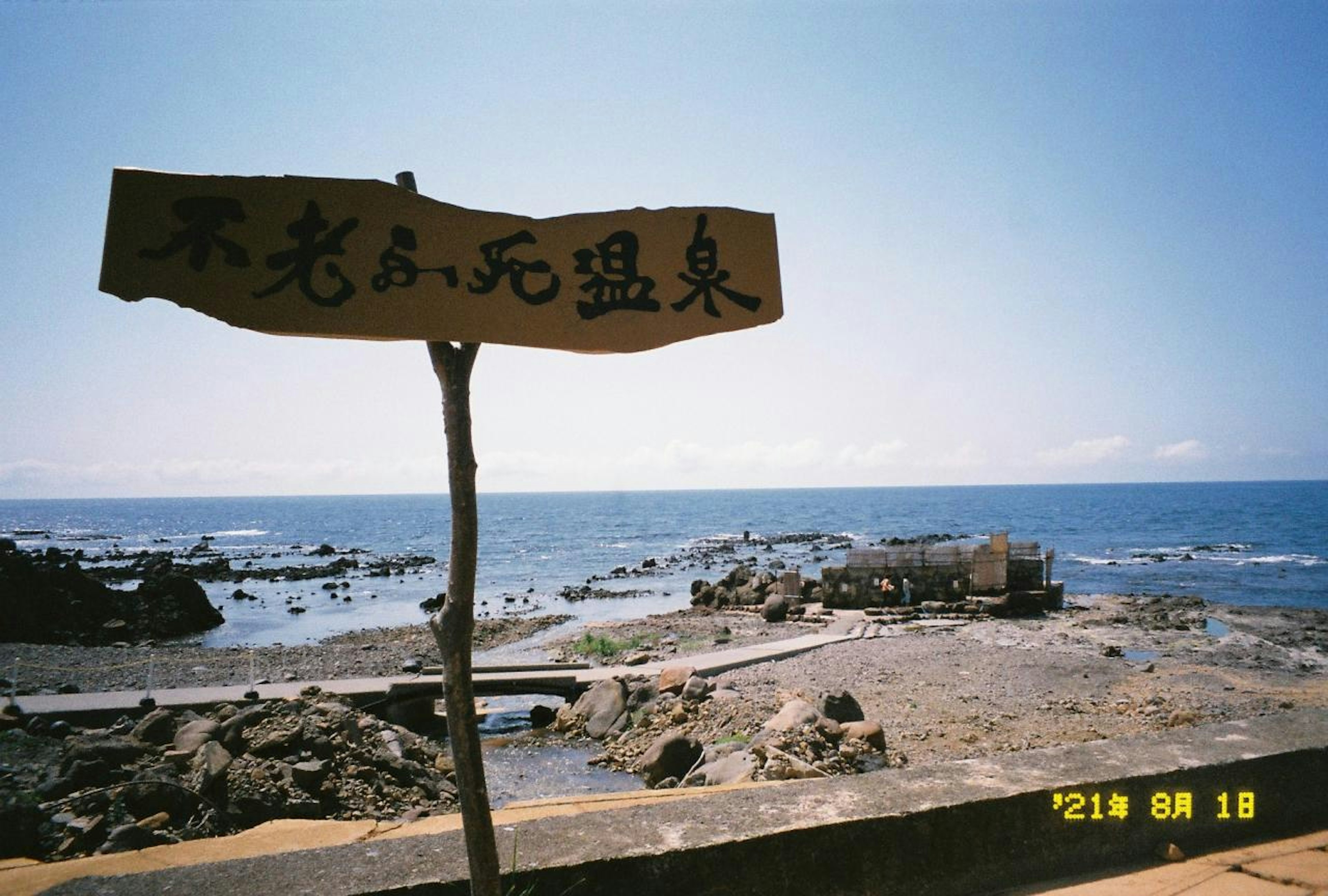 海の近くに立つ木製の看板と岩のビーチ