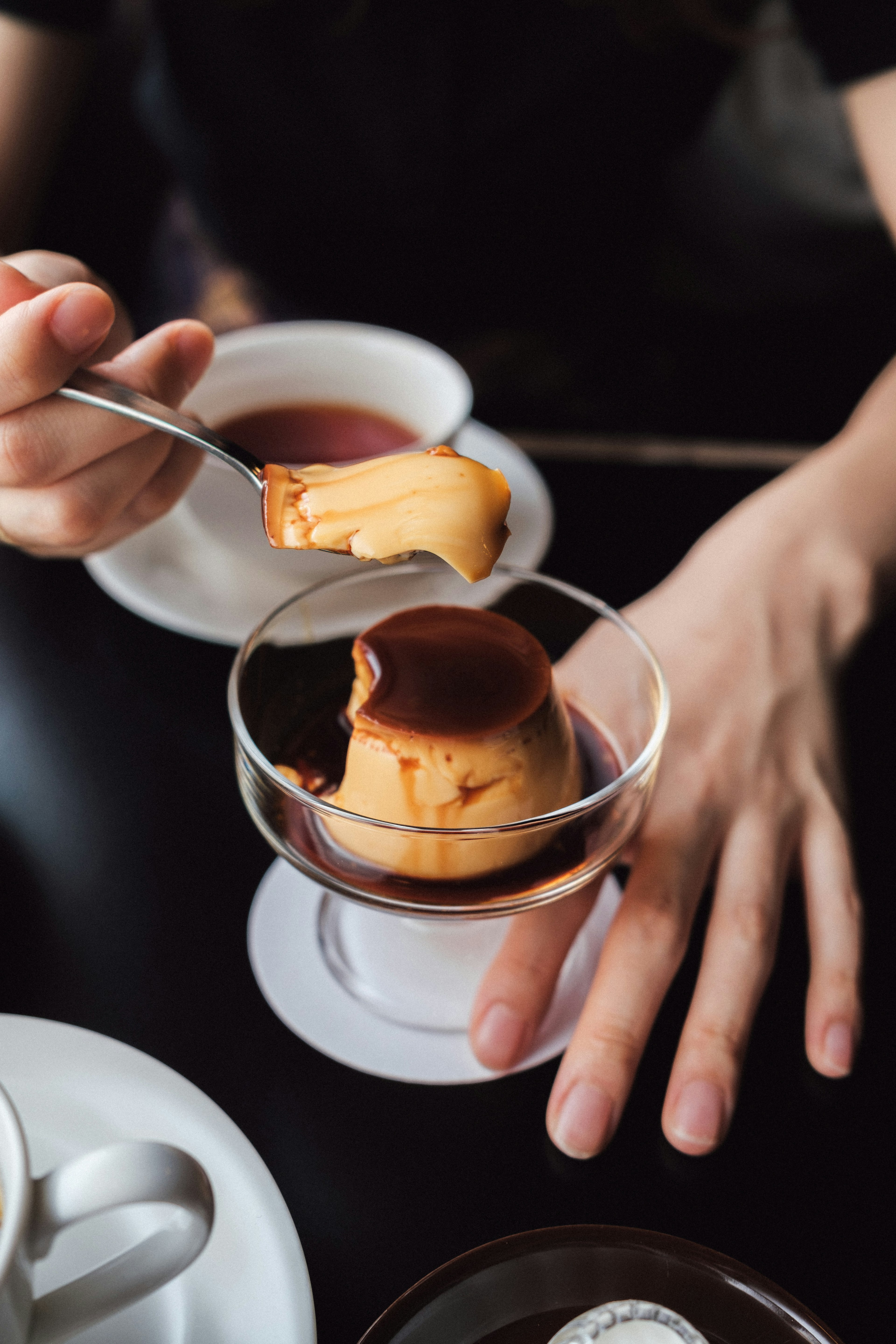 A hand lifting a custard pudding with a spoon