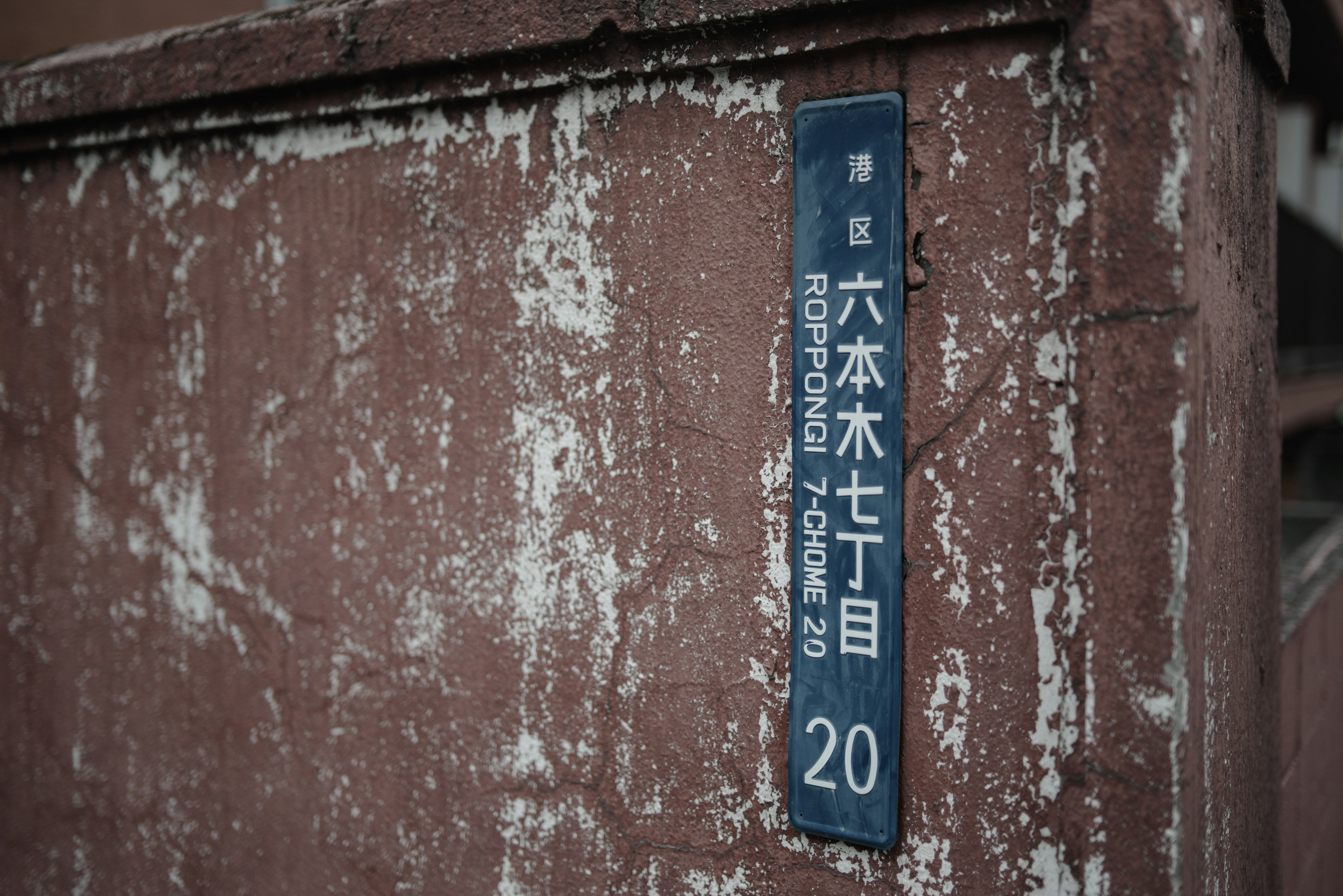 Panneau d'adresse bleu sur un vieux mur Roppongi 7-chome 20