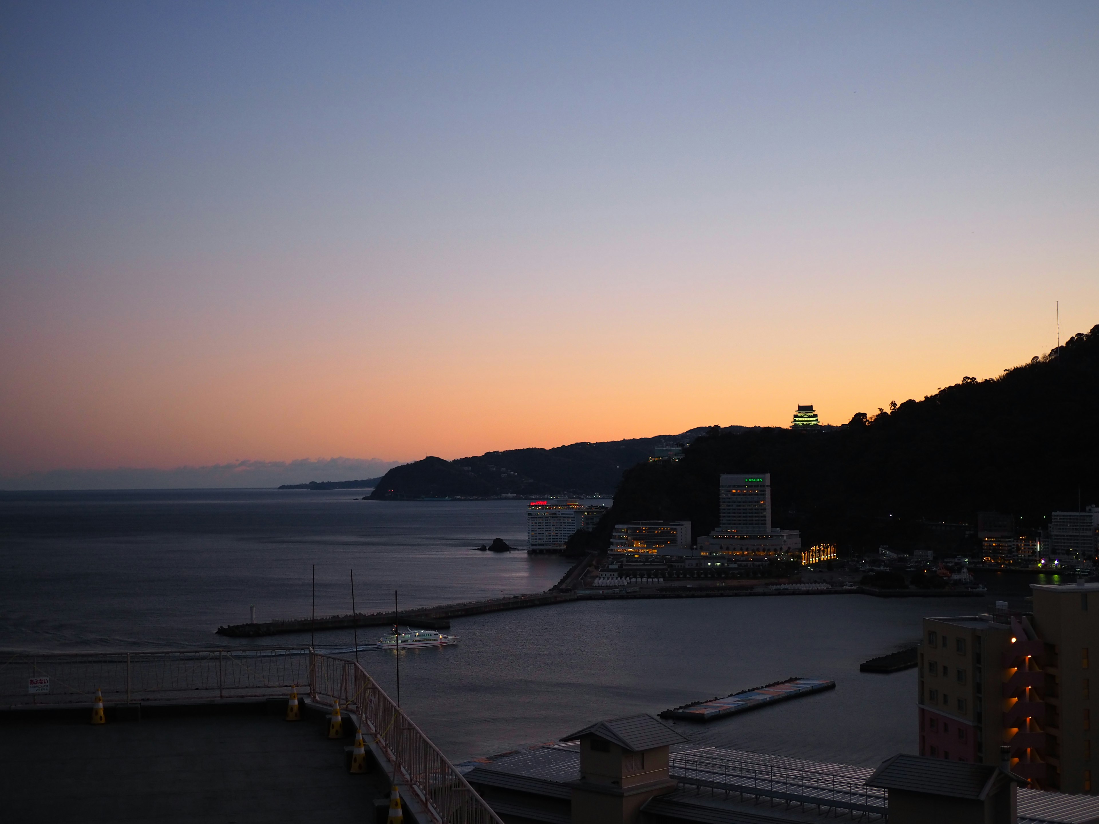 夕暮れの海と山の風景に明かりがともる