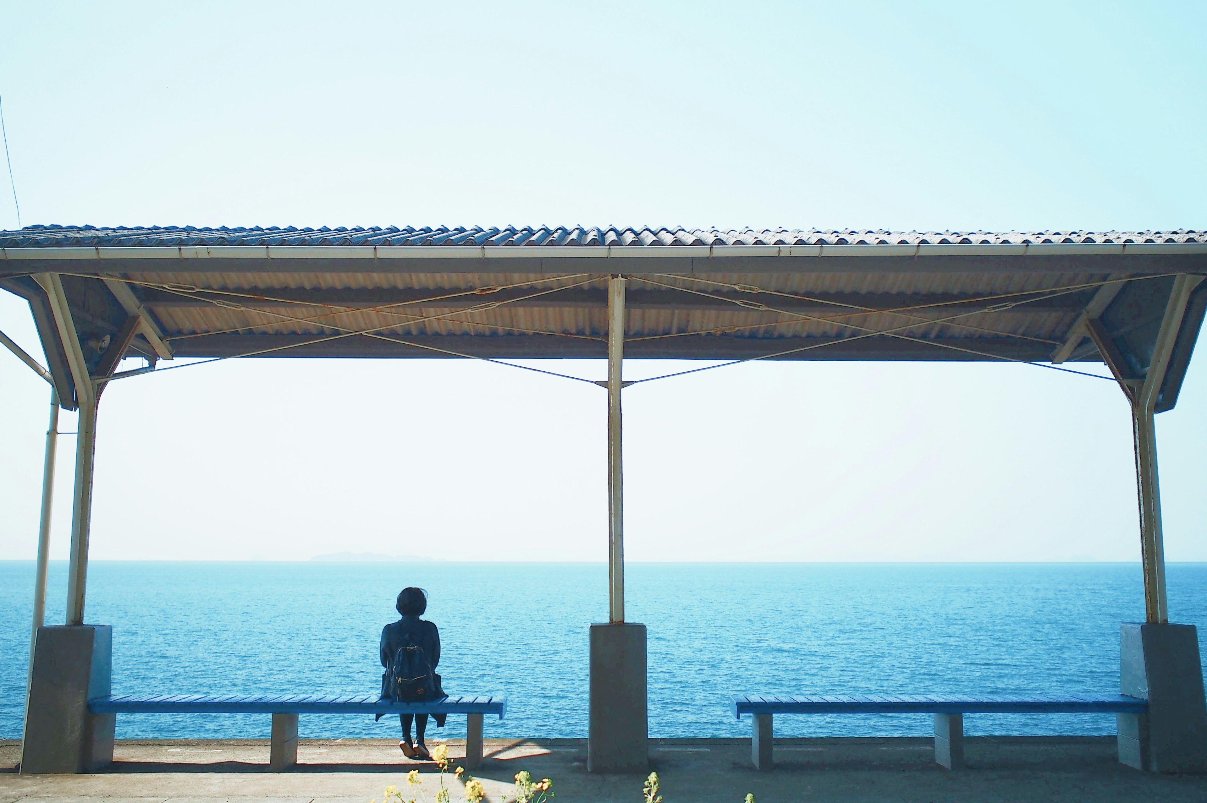 Silhouette of a person looking at the sea under a pavilion