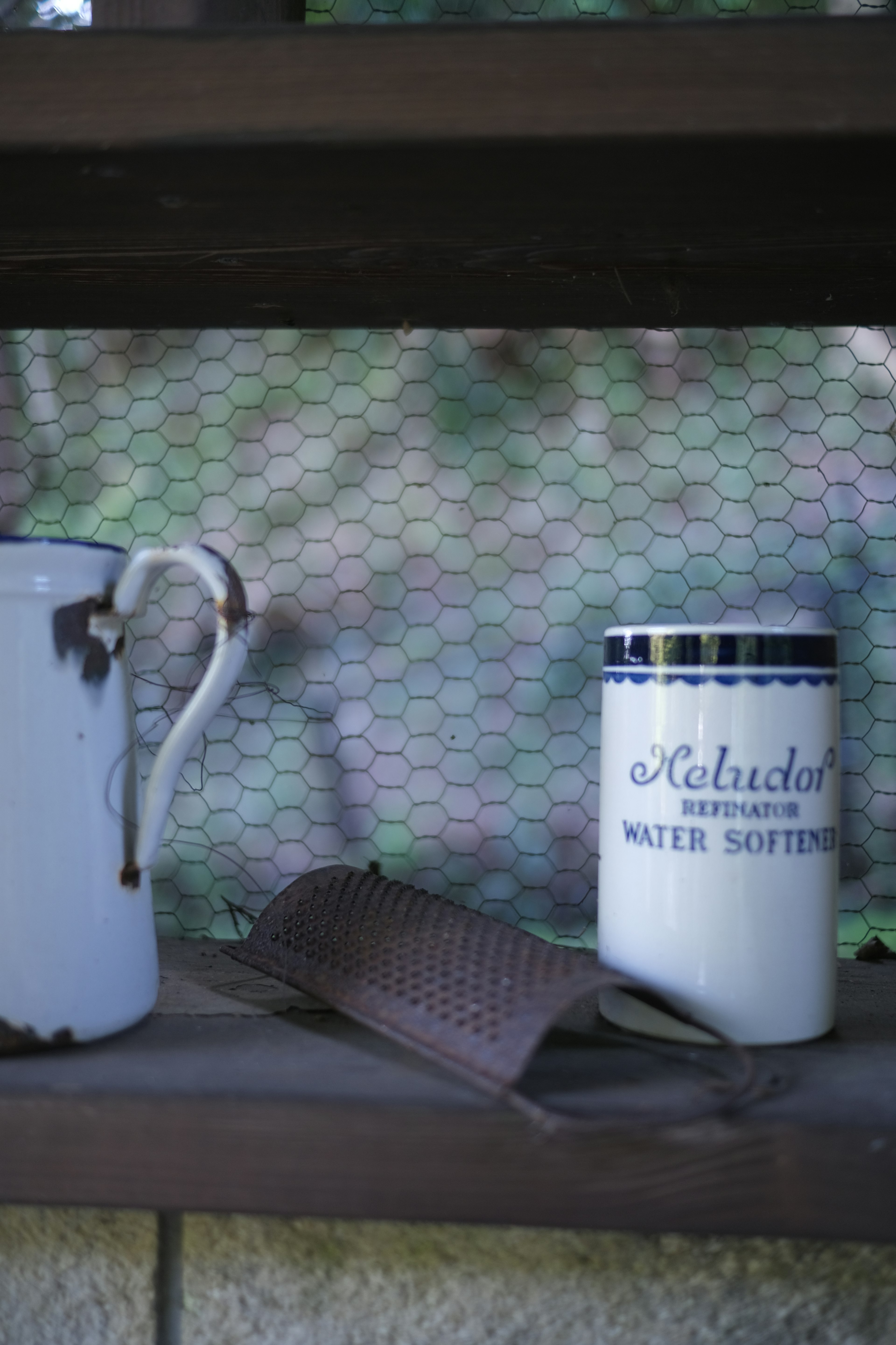 A white mug and an old pot displayed on a shelf