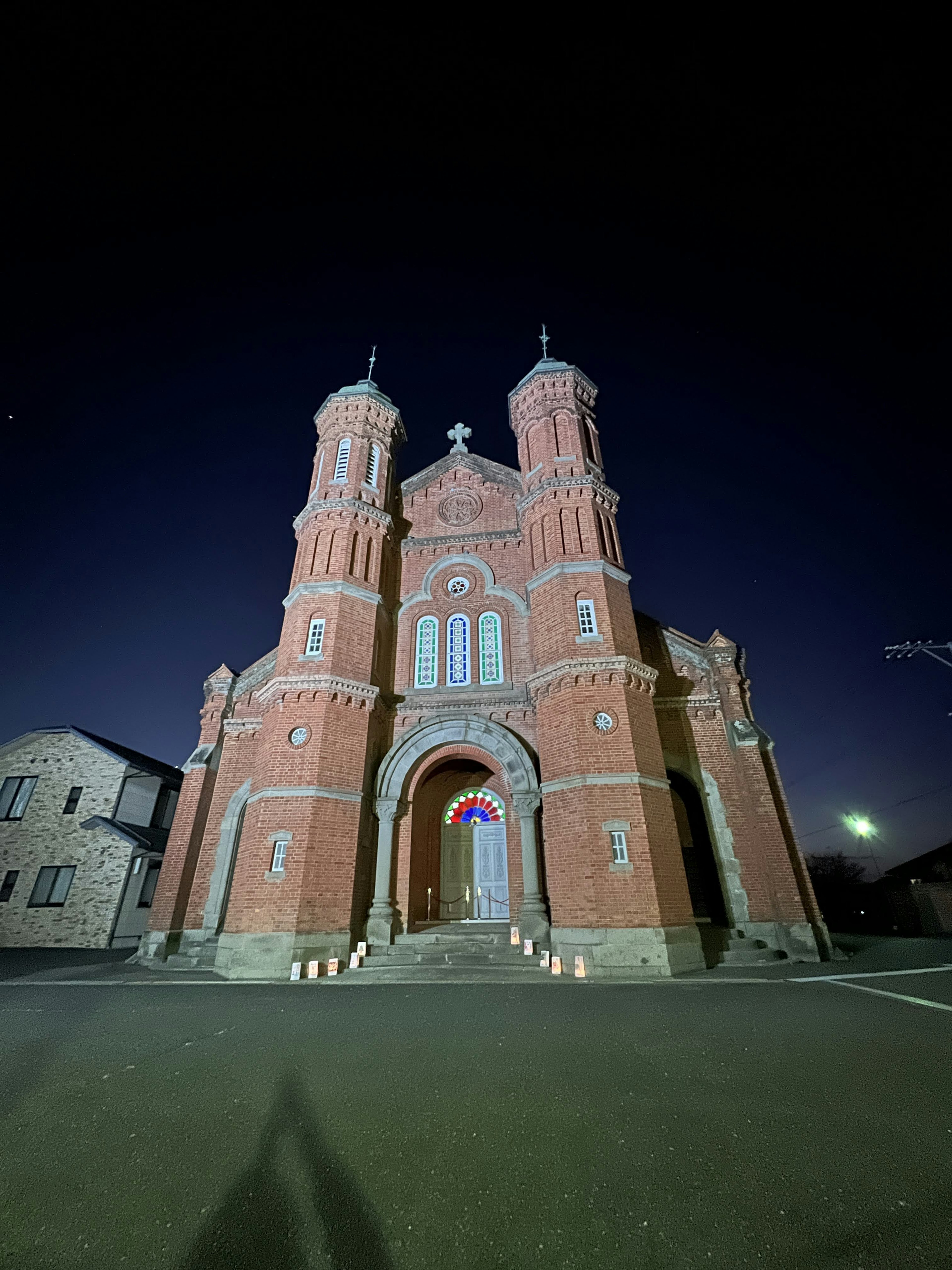 Façade de l'église en brique rouge avec deux tours la nuit