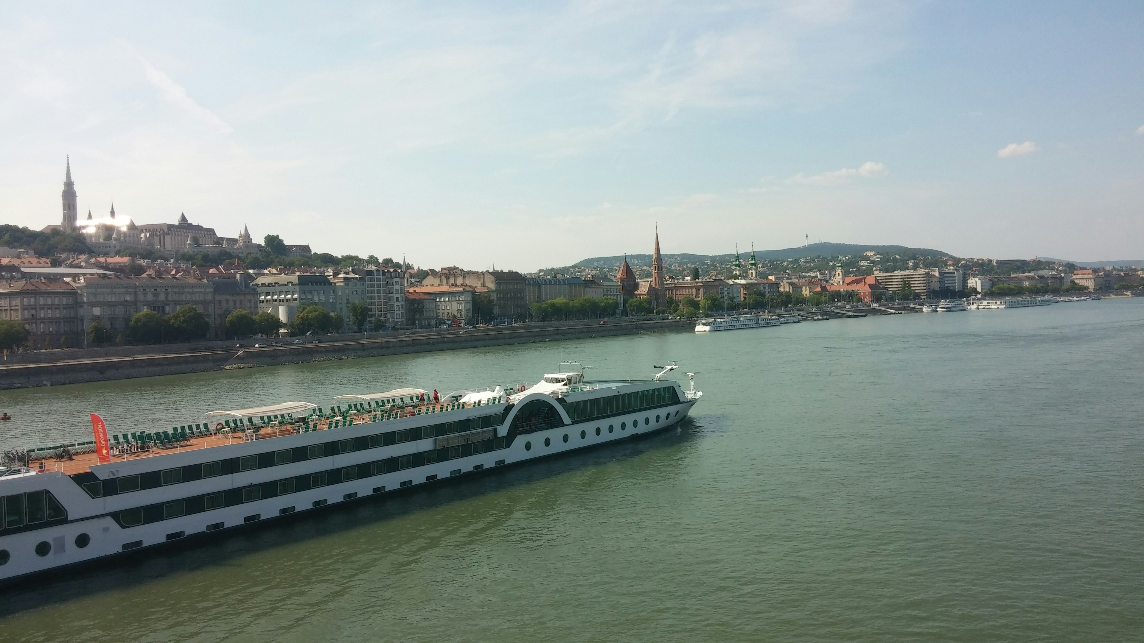 Barco de crucero navegando por el río Danubio con edificios de fondo