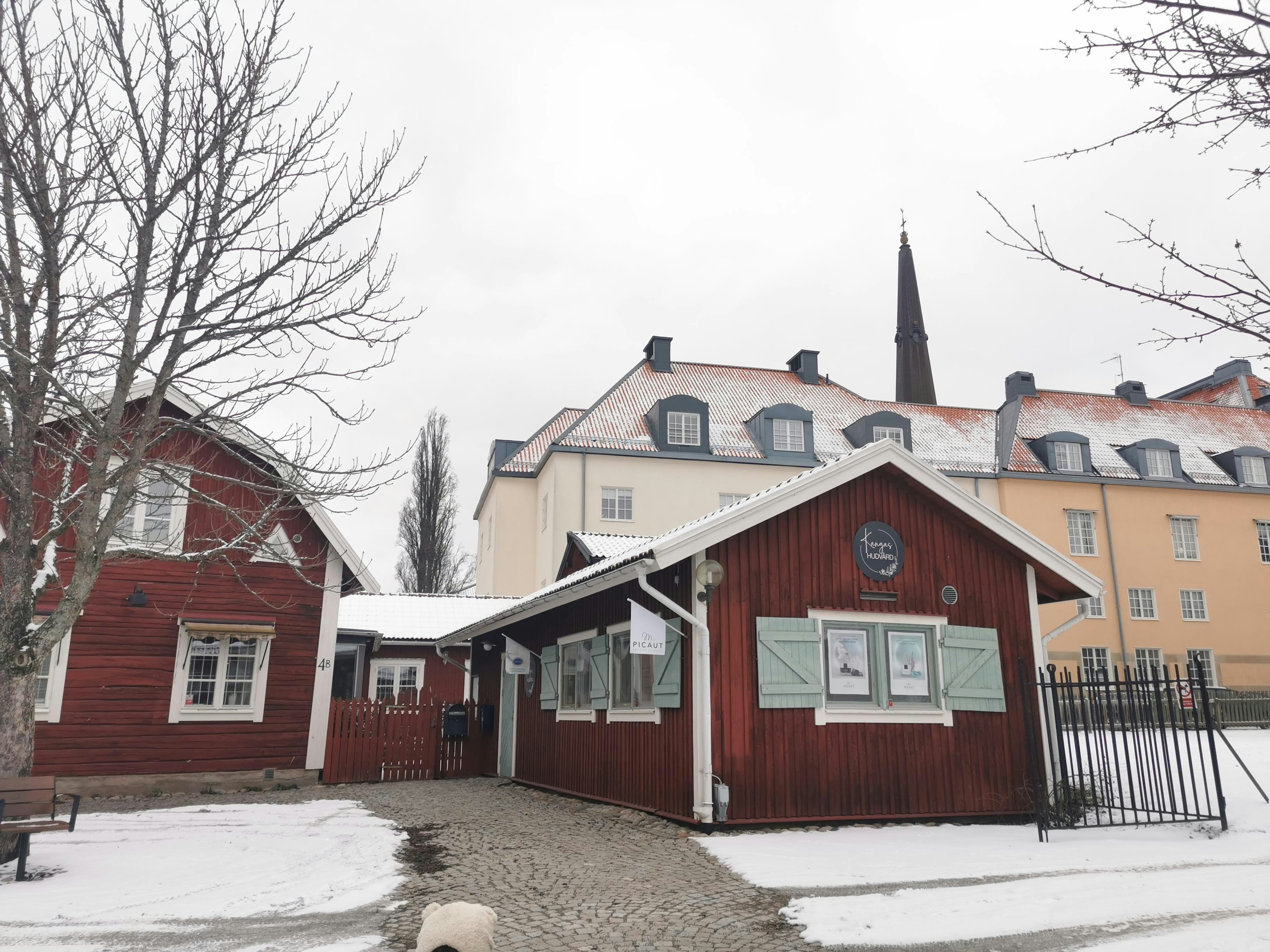 Schneebedecktes rotes Holzhaus neben einem weißen Gebäude